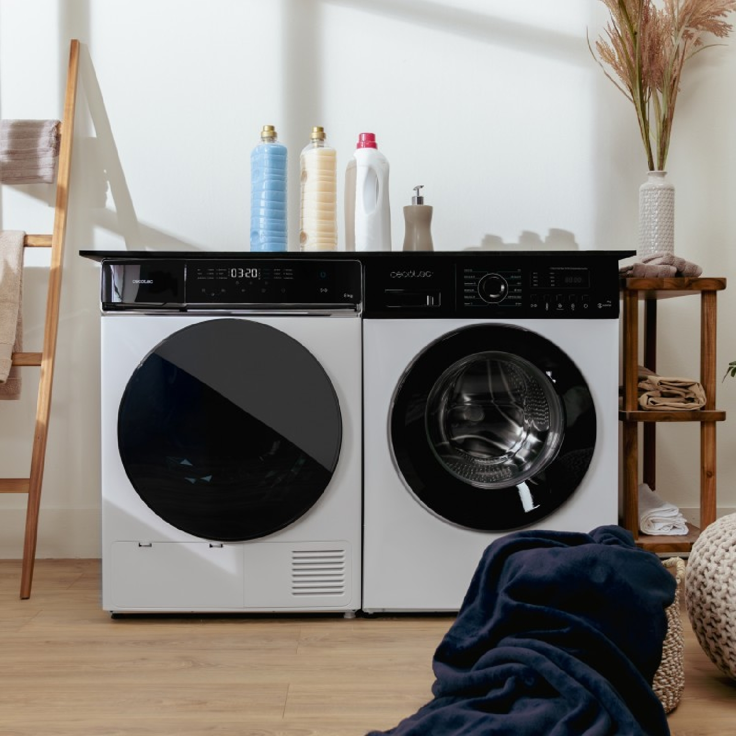 Dos lavadoras blancas están una al lado de la otra en una habitación luminosa, con botellas encima.
