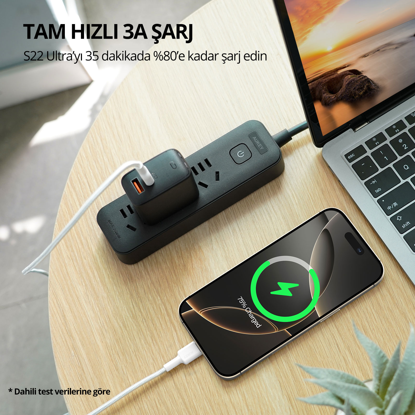 Ahşap bir masa üzerinde, akıllı telefon ve dizüstü bilgisayara bağlı siyah bir uzatma kablosu.