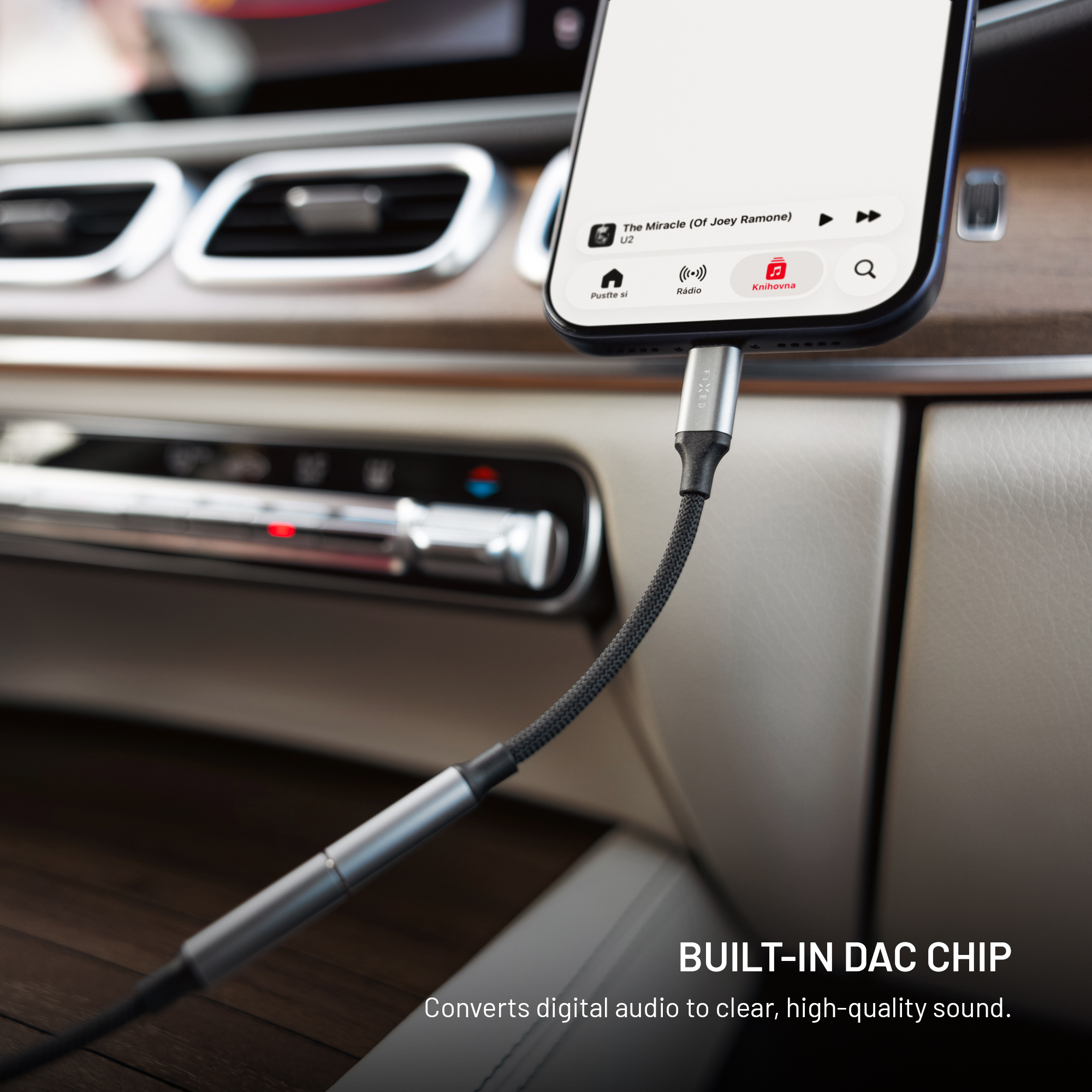 Ein Smartphone ist mit einem Audiokabel in einer modernen Autokonsole verbunden.