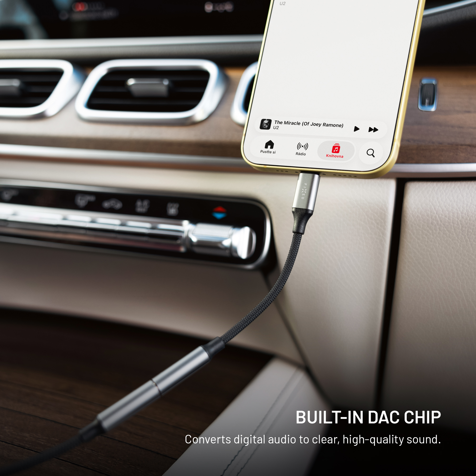 Smartphone im Auto-Armaturenbrett, verbunden mit einem schwarzen geflochtenen Aux-Kabel.