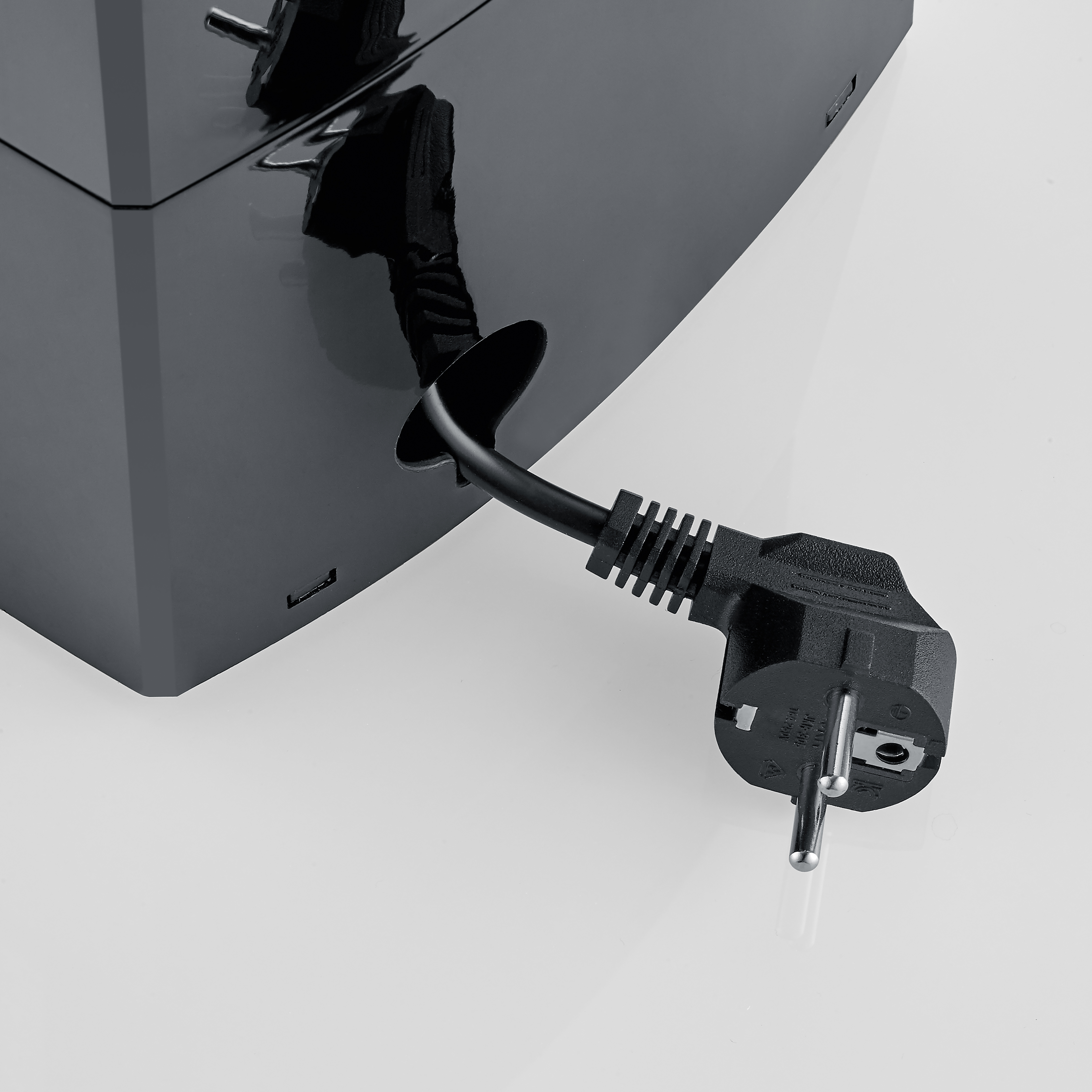 Ein schwarzes Netzkabel mit Schukostecker kommt aus einem glänzenden schwarzen Gehäuse.