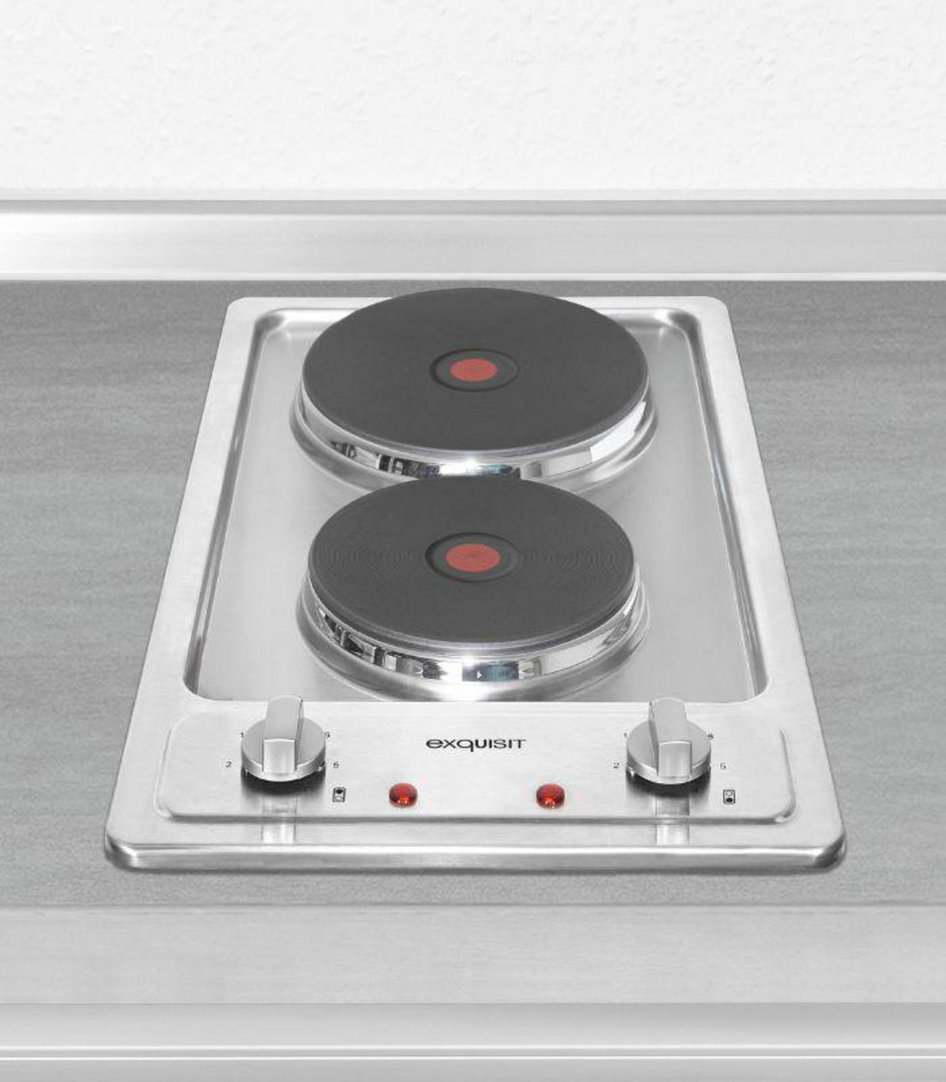 Ein silberner Exquisit-Elektroherd mit zwei schwarzen Kochplatten und zwei Bedienknöpfen auf einer grauen Arbeitsplatte.