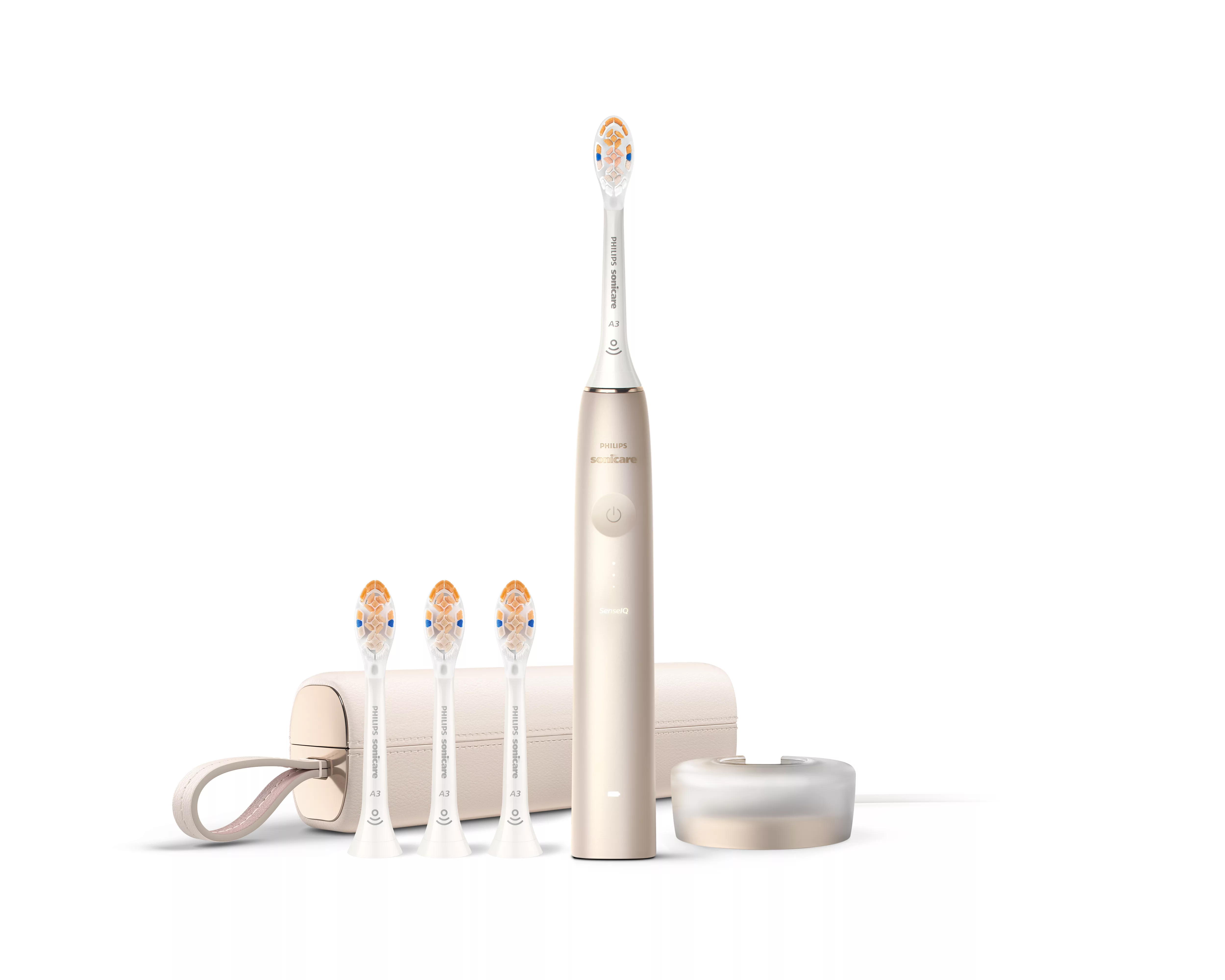 Goldfarbene Philips Sonicare Zahnbürste mit drei Ersatzbürsten, Etui und Ladestation vor weißem Hintergrund.
