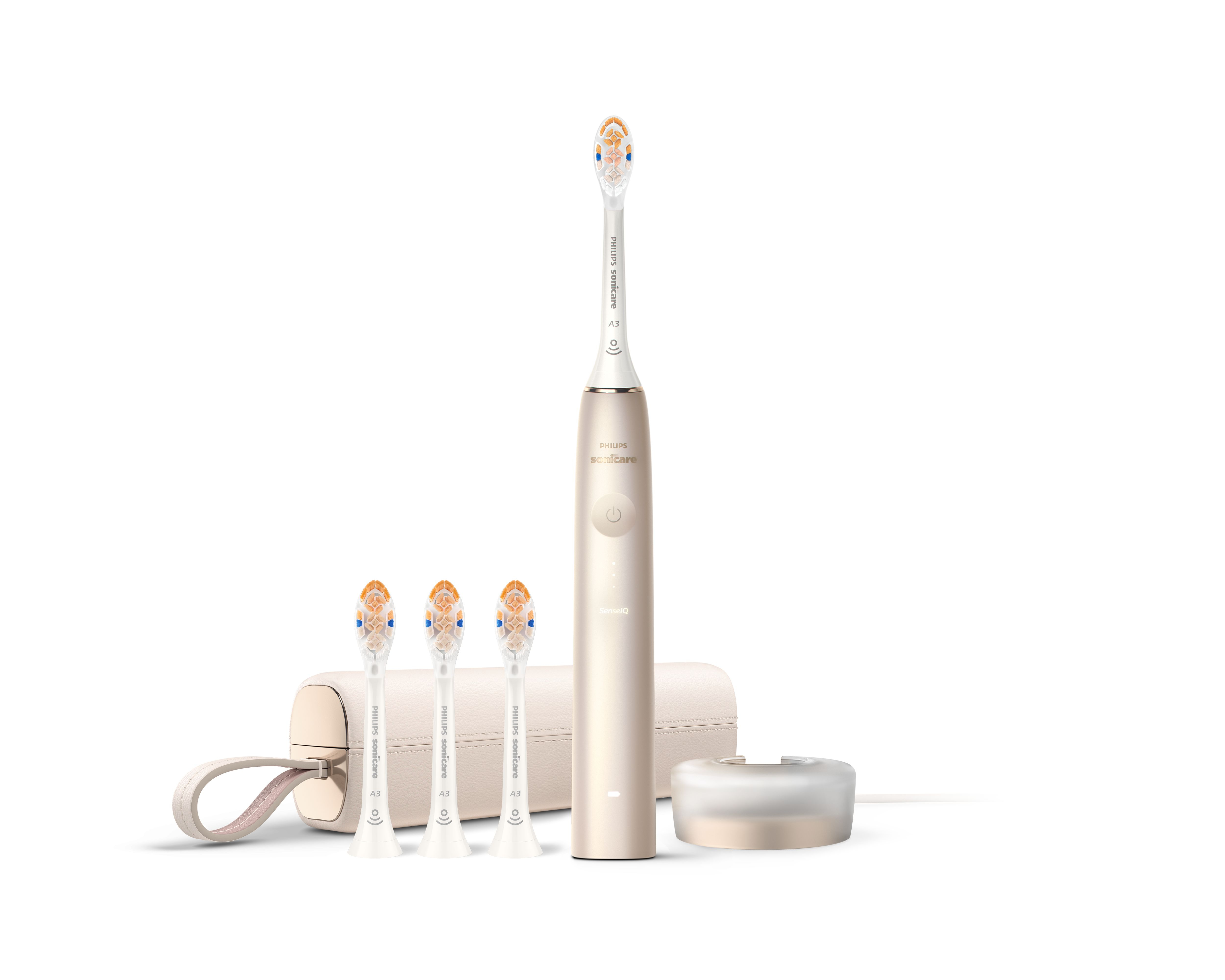 Eine goldene Philips Sonicare Zahnbürste mit Ersatzbürsten, Reiseetui und Ladestation auf weißem Hintergrund.