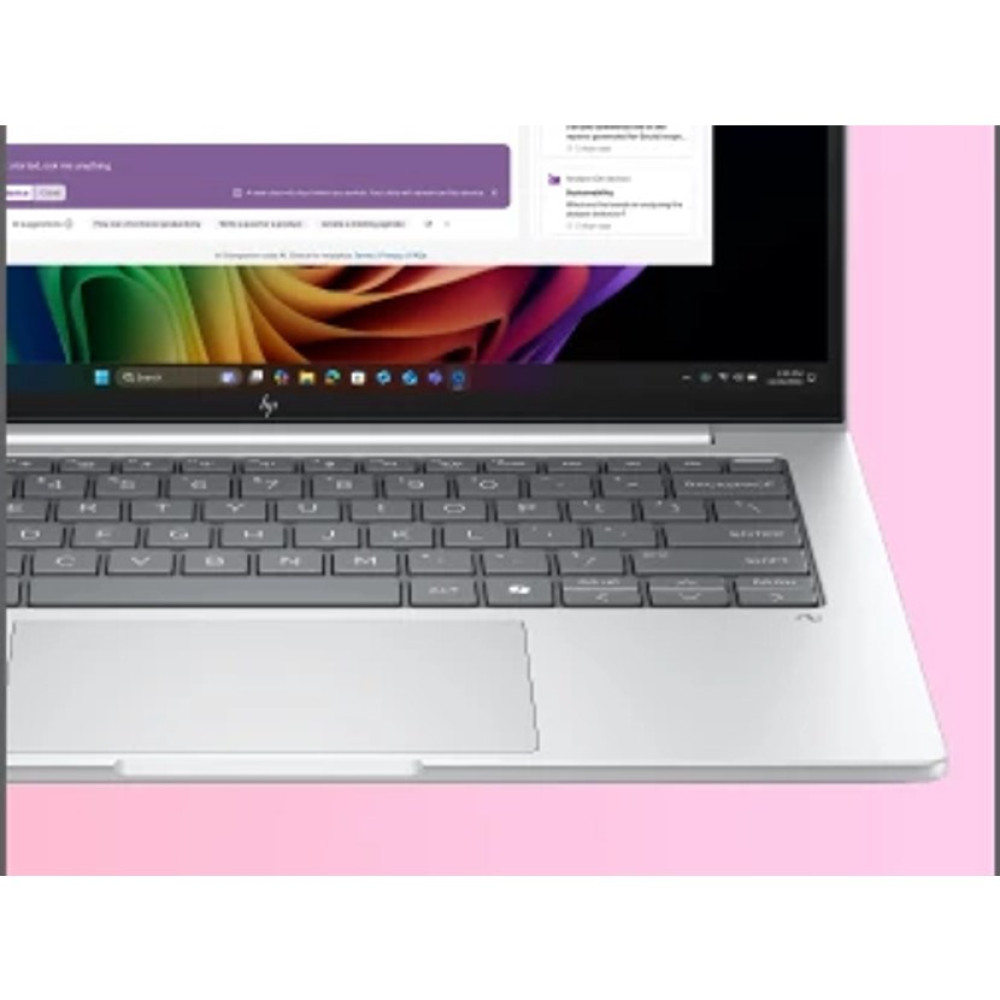 Zbliżenie srebrnej klawiatury laptopa i gładzika na różowym tle.