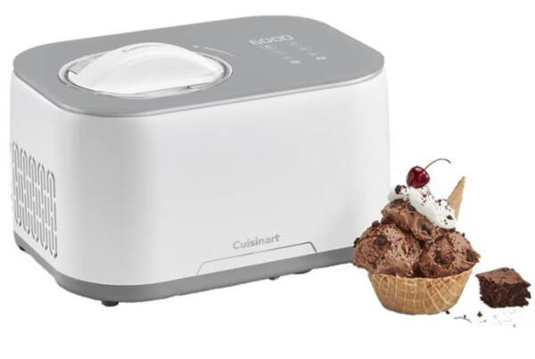 Una heladera Cuisinart blanca junto a un bol de gofres con helado de chocolate, nata y una cereza.