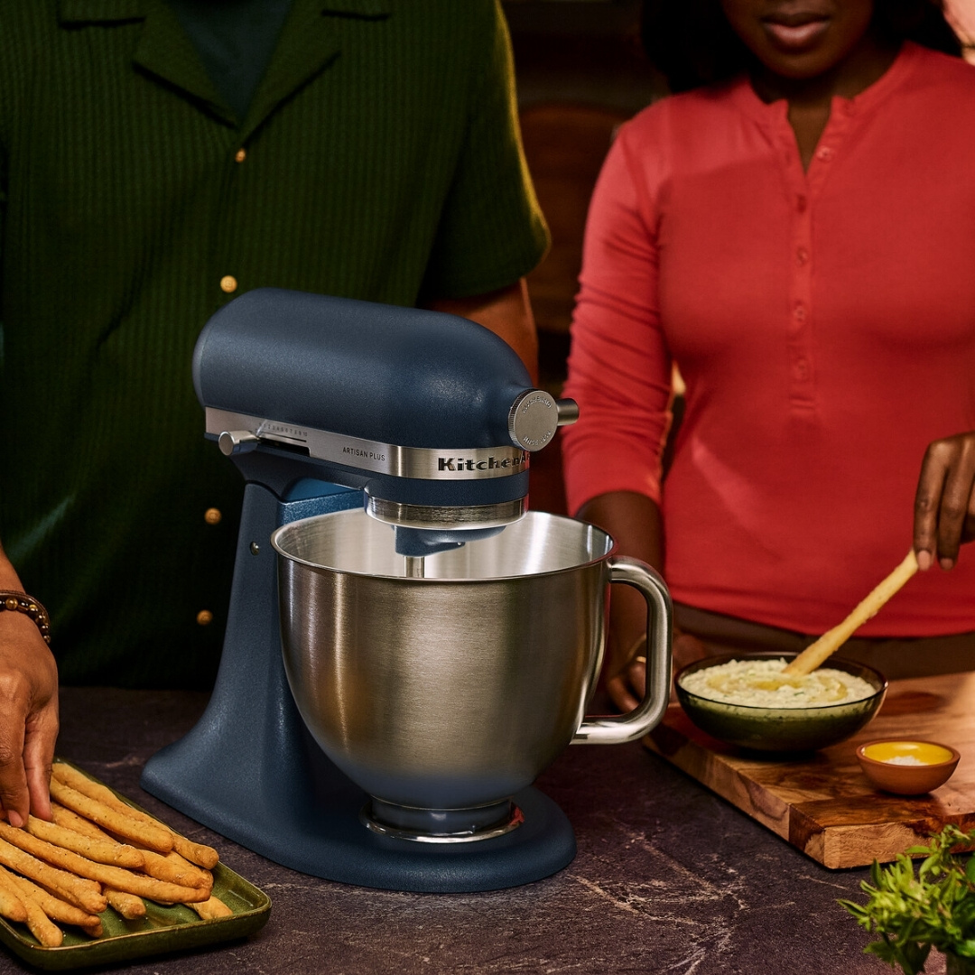 Mavi bir KitchenAid mikser, ekmek çubukları ve bir kase sosun yanında tezgah üzerinde duruyor.