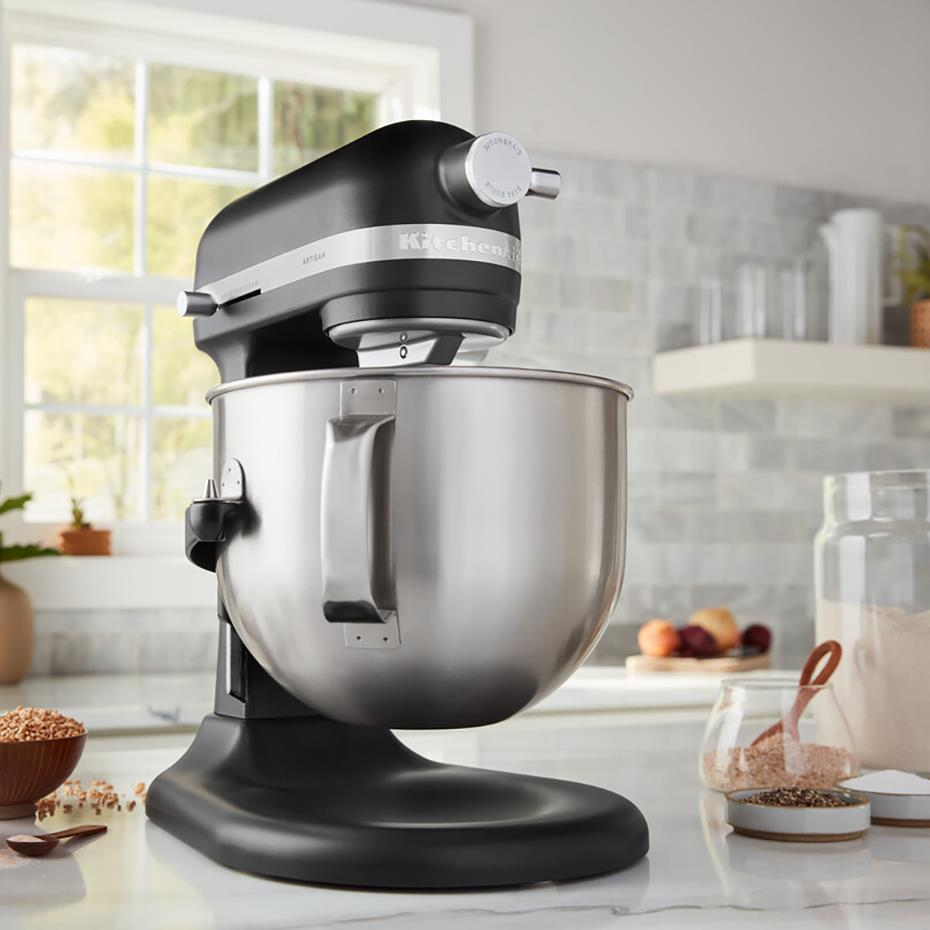 Eine schwarze KitchenAid Küchenmaschine mit Edelstahlschüssel auf einer Theke, mit Backzutaten.