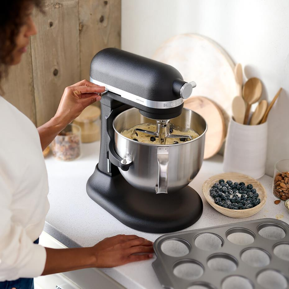 Eine Frau schaltet eine schwarze Küchenmaschine in einer Küche ein.