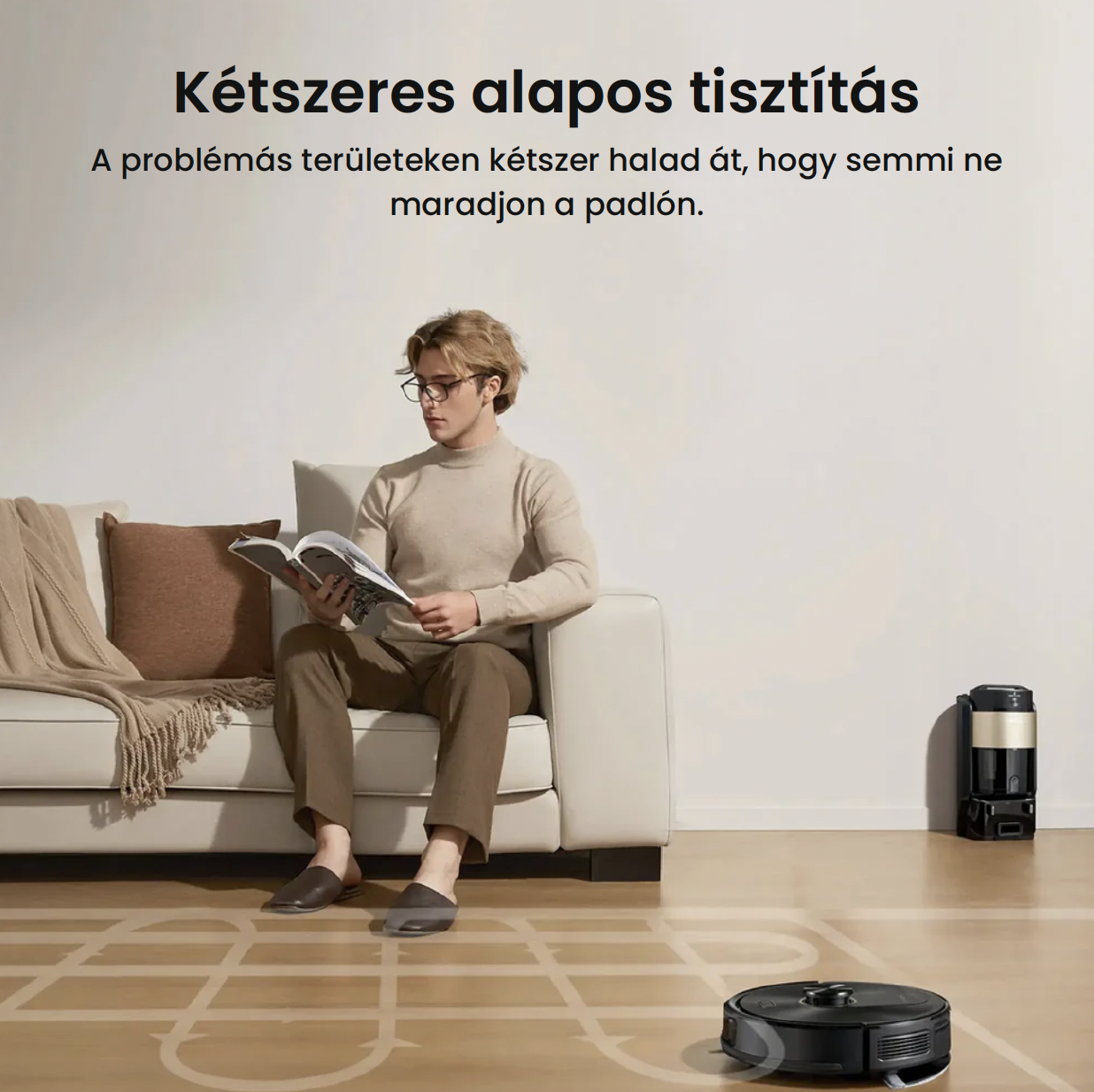Un uomo siede su un divano leggendo mentre un robot aspirapolvere pulisce.