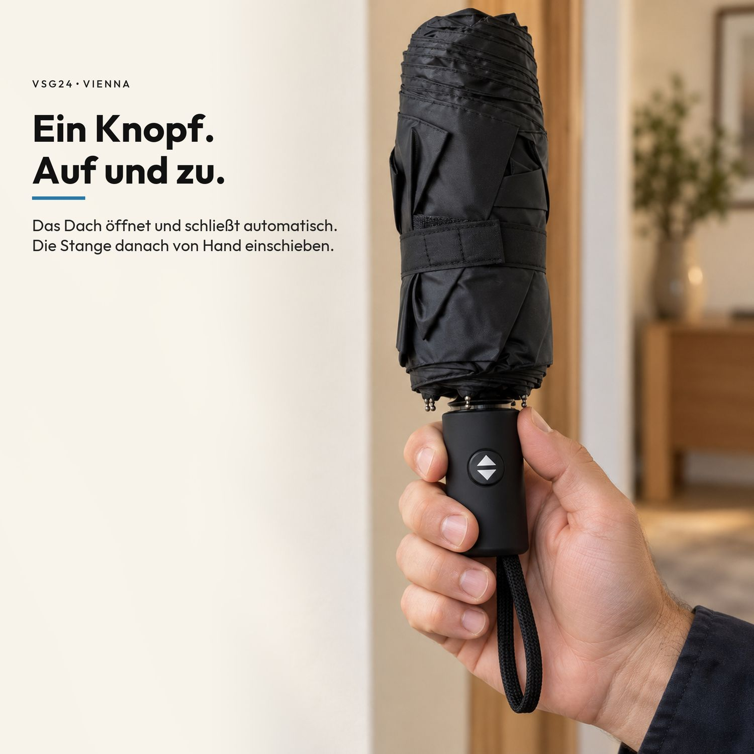 Hand hält einen geschlossenen schwarzen Regenschirm mit einem Knopf am Griff in einem Innenraum.