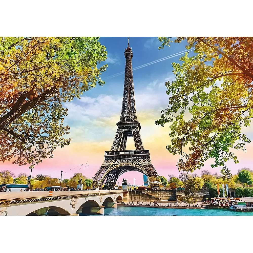 The Eiffel Tower framed by autumn trees, with a stone bridge over the river in the foreground under a colorful sky.