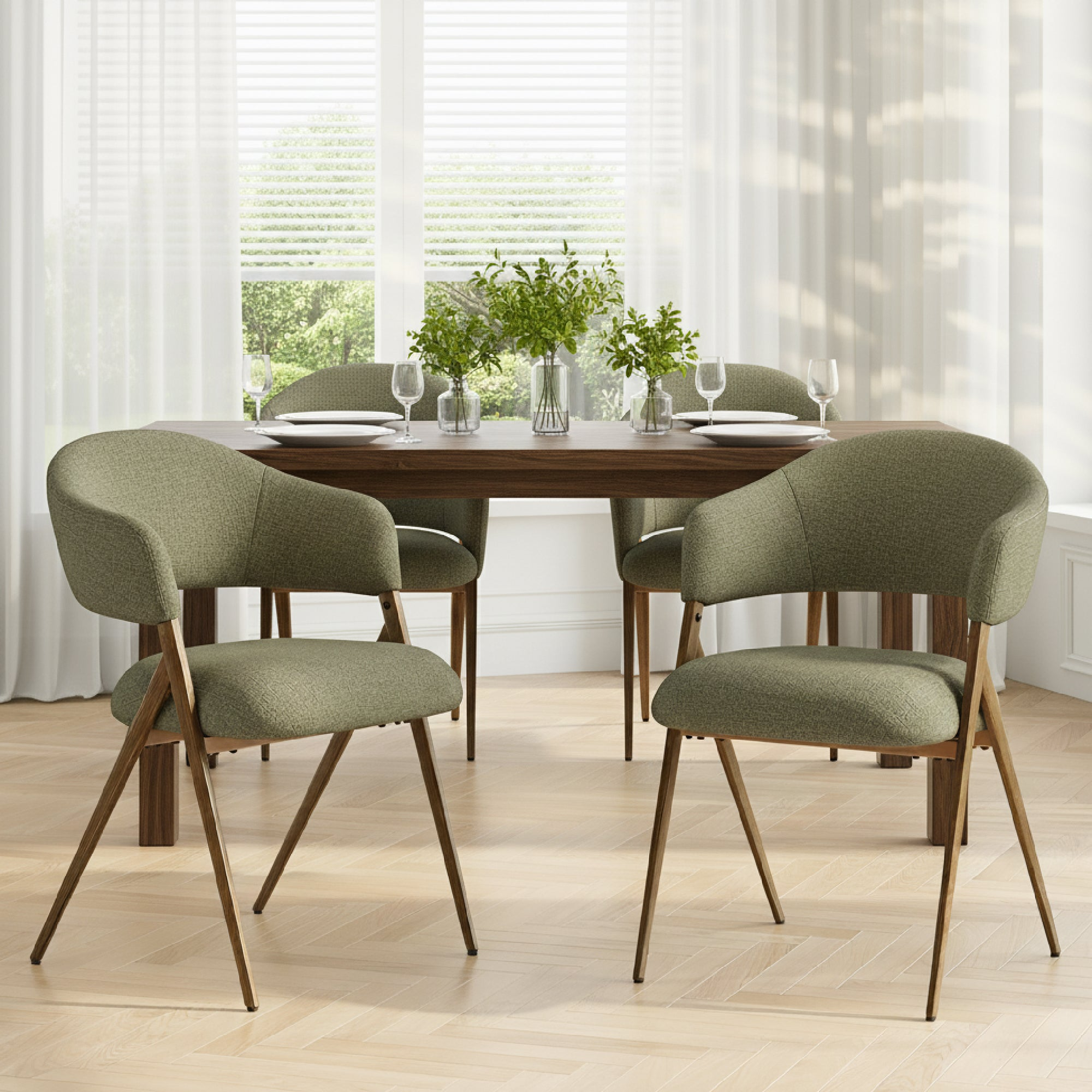 Una sala da pranzo con tavolo in legno, sedie verdi imbottite e vasi di piante verdi davanti a grandi finestre.