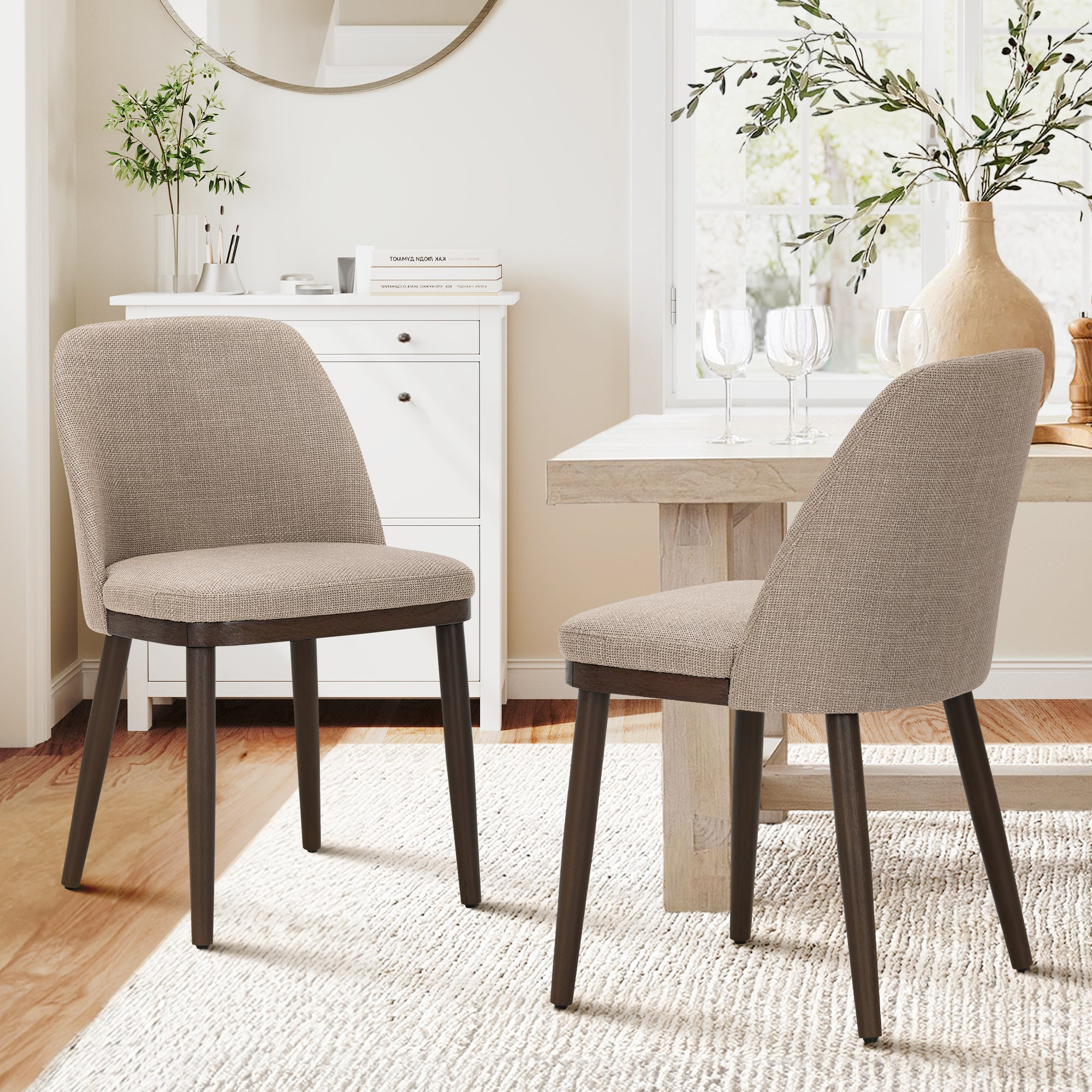 Due sedie da pranzo imbottite in beige con gambe in legno scuro vicino a un tavolo di legno.