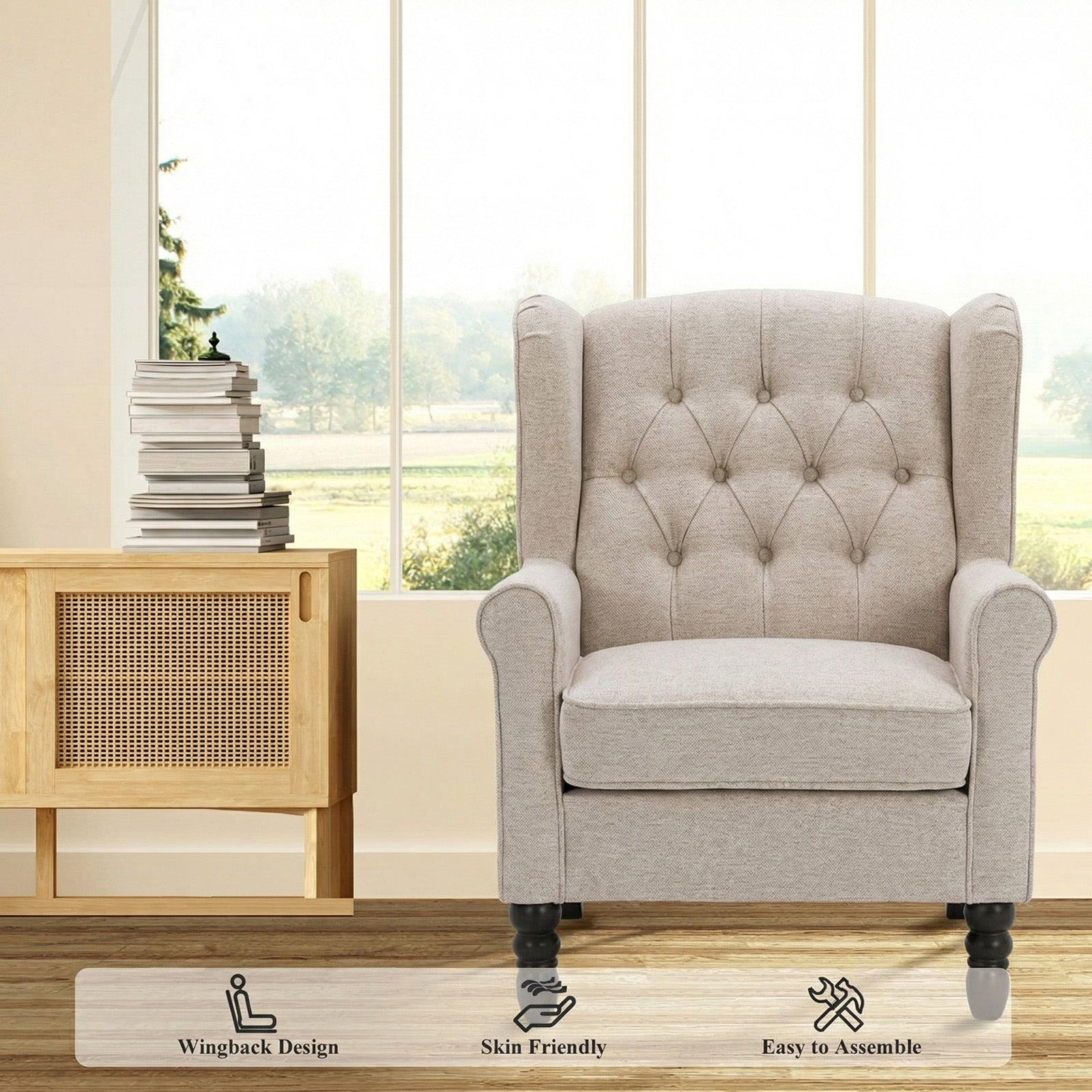 Poltrona orecchiona beige trapuntata vicino a un mobile in legno con libri.