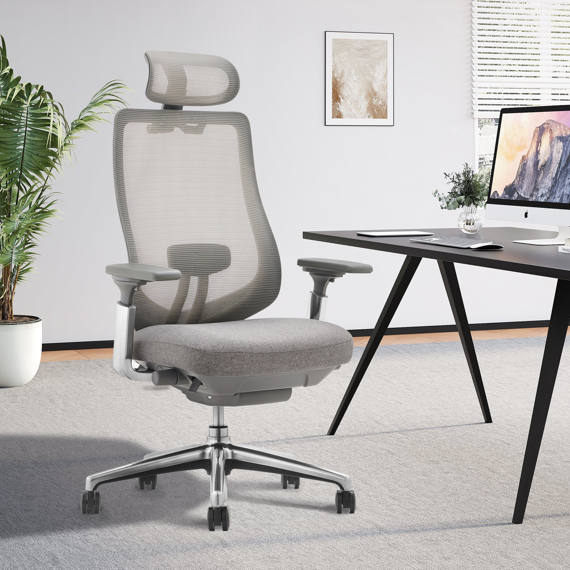 Moderner grauer Bürostuhl mit Rollen in einem hellen Arbeitszimmer mit Schreibtisch und Computer.
