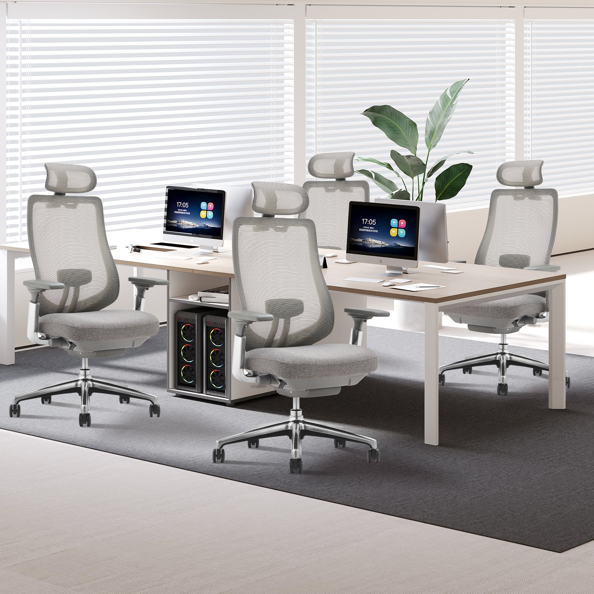 Moderne Arbeitsplätze mit ergonomischen Stühlen, Computern und Pflanzen vor großen Jalousiefenstern.