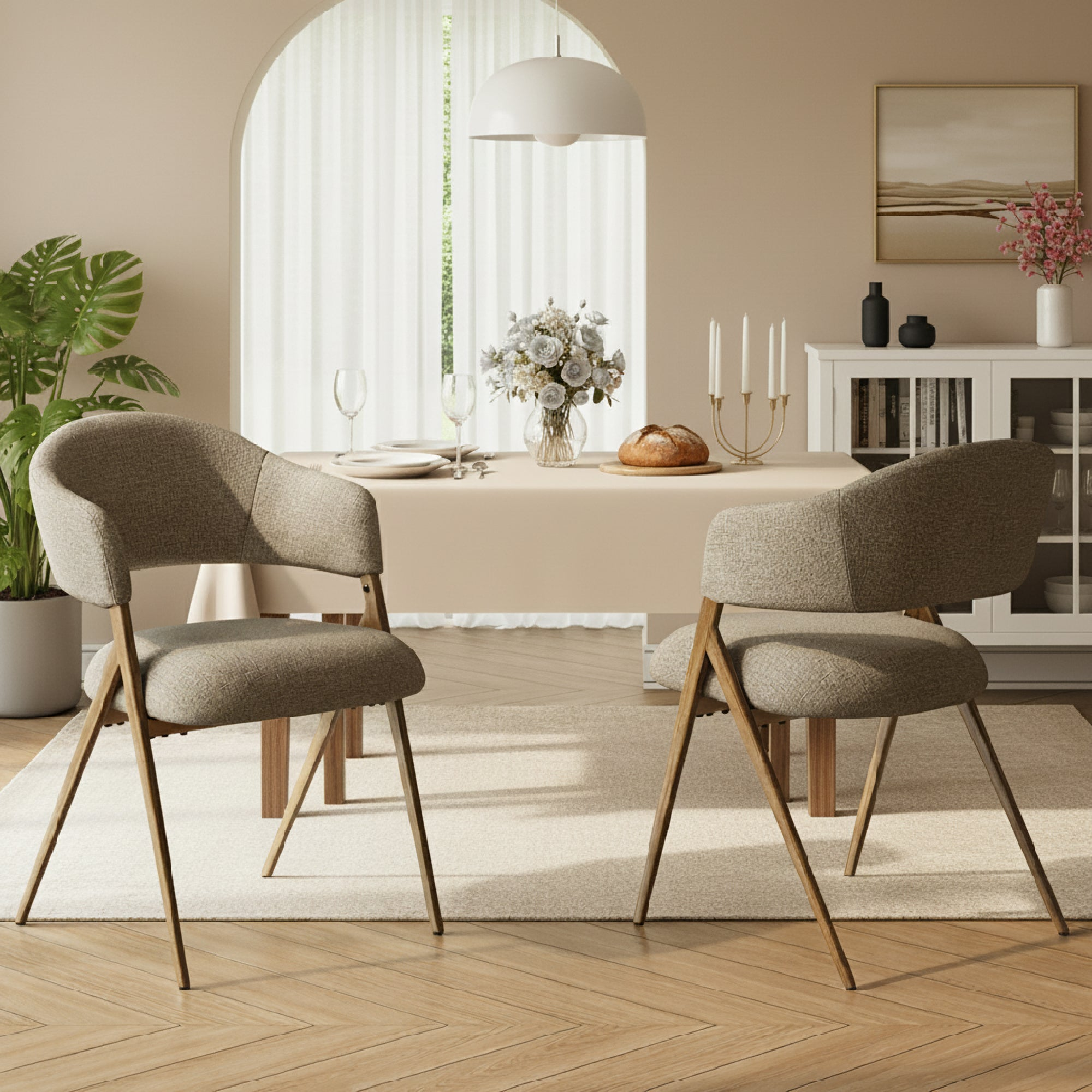 Una sala da pranzo con due sedie imbottite in primo piano e una tavola apparecchiata dietro.
