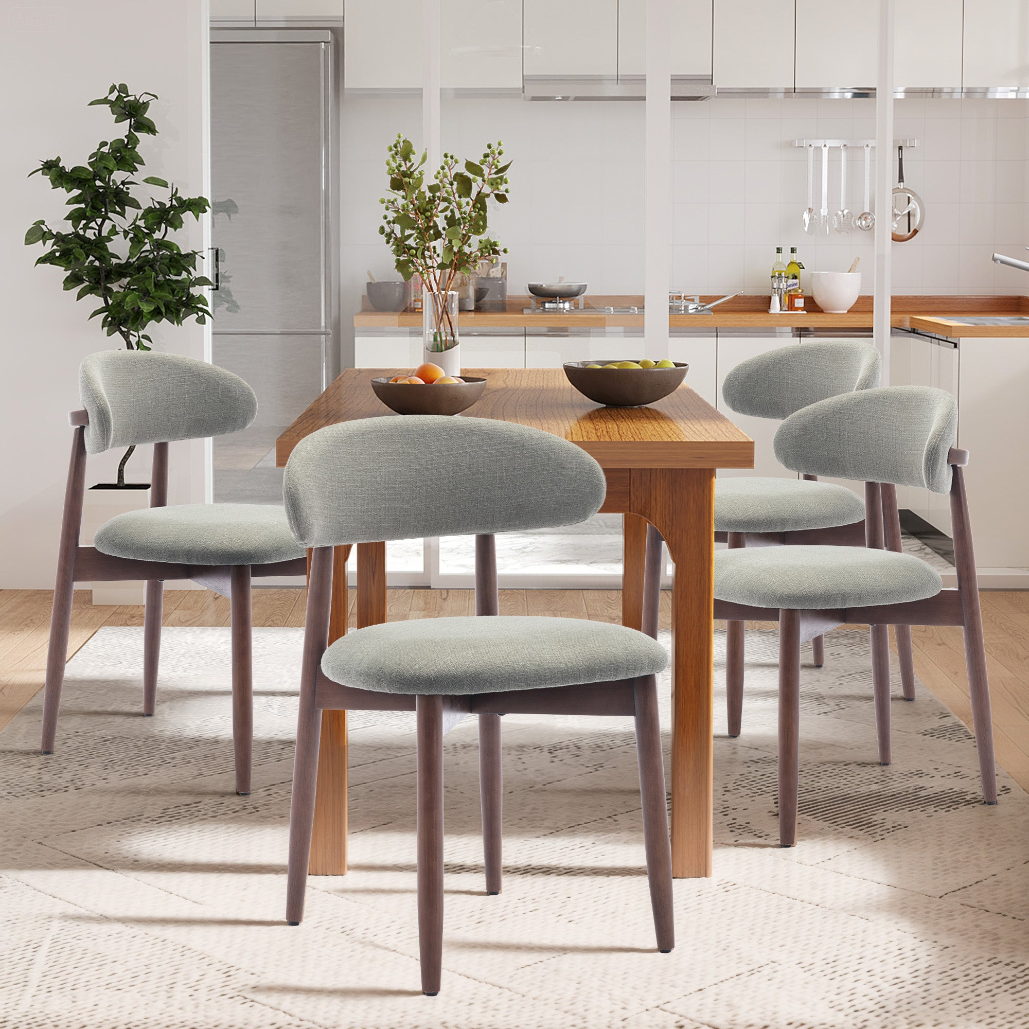 Esszimmer mit Holztisch und vier grau gepolsterten Stühlen auf einem Teppich, im Hintergrund eine helle Küche.