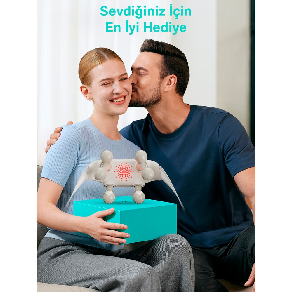 Bir adam gülen bir kadını yanağından öpüyor, kadın ise hediye kutusu üzerinde masaj aleti tutuyor.
