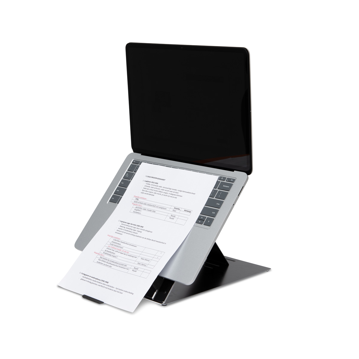 Ein silberner Laptop steht auf einem schwarzen Ständer, mit einem bedruckten Papier auf der Tastatur.