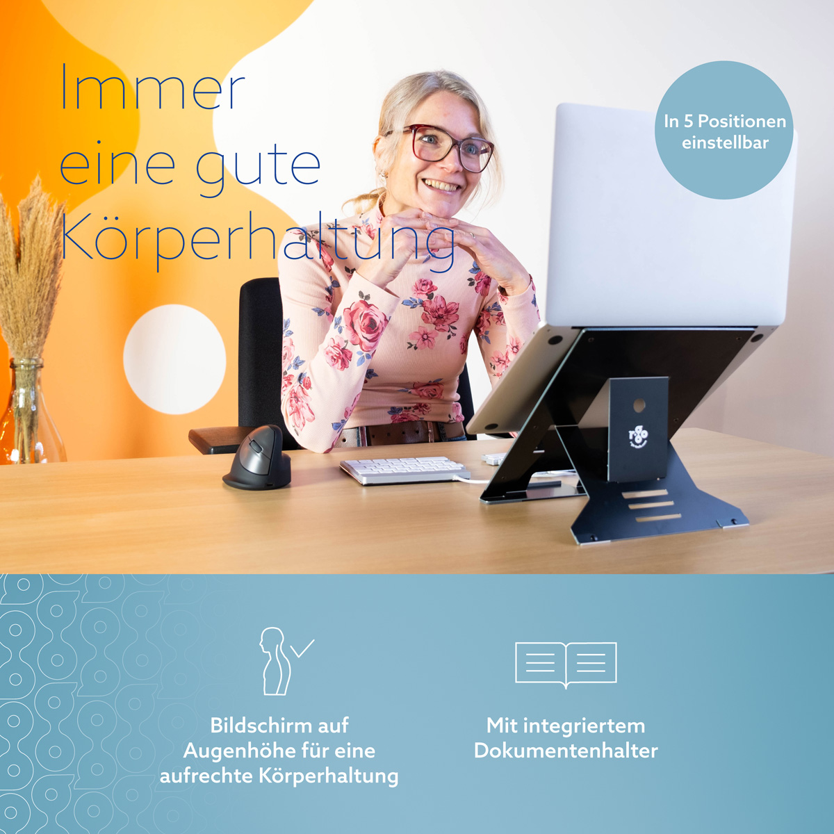 Frau sitzt am Schreibtisch und arbeitet am Laptop auf einem schwarzen Ständer.