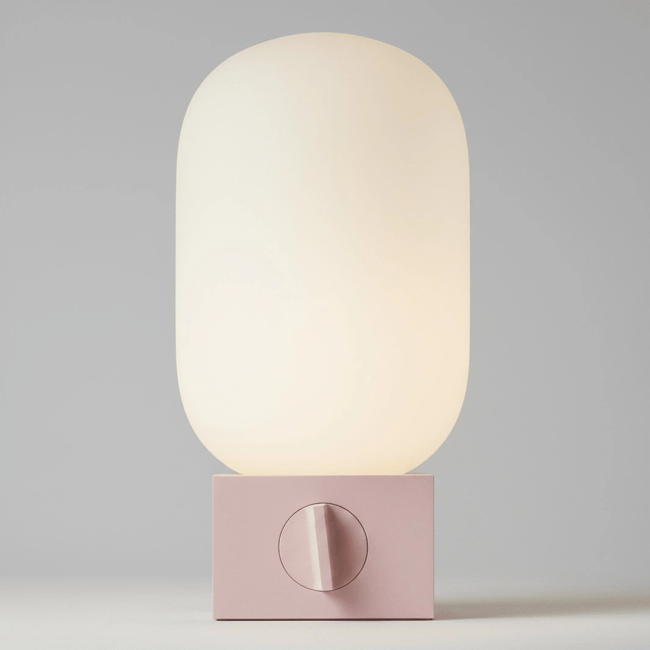 Owalna, świecąca lampa stołowa z różową podstawą i pokrętłem na jasnym tle.