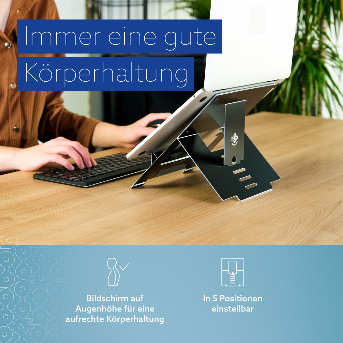 Ein Laptop auf einem verstellbaren schwarzen Ständer auf einem Holztisch, eine Person tippt.