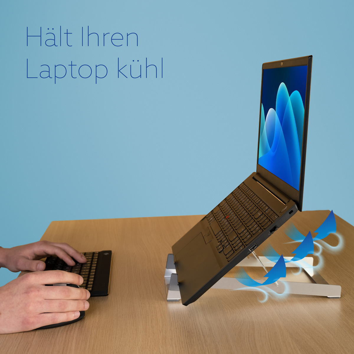 Ein Laptop auf einem silbernen Ständer auf Holz, mit blauen Luftstrompfeilen und den Worten 'Hält Ihren Laptop kühl'.