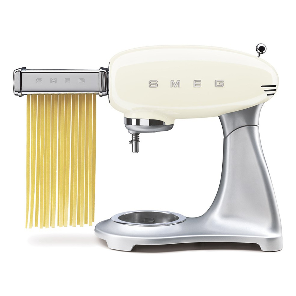 Beigefarbene Smeg-Küchenmaschine mit silbernem Ständer und Nudelaufsatz, der frische Spaghetti extrudiert.