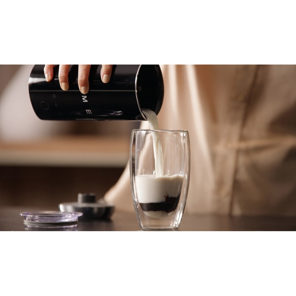 Se vierte leche de un recipiente negro en un vaso con chocolate.