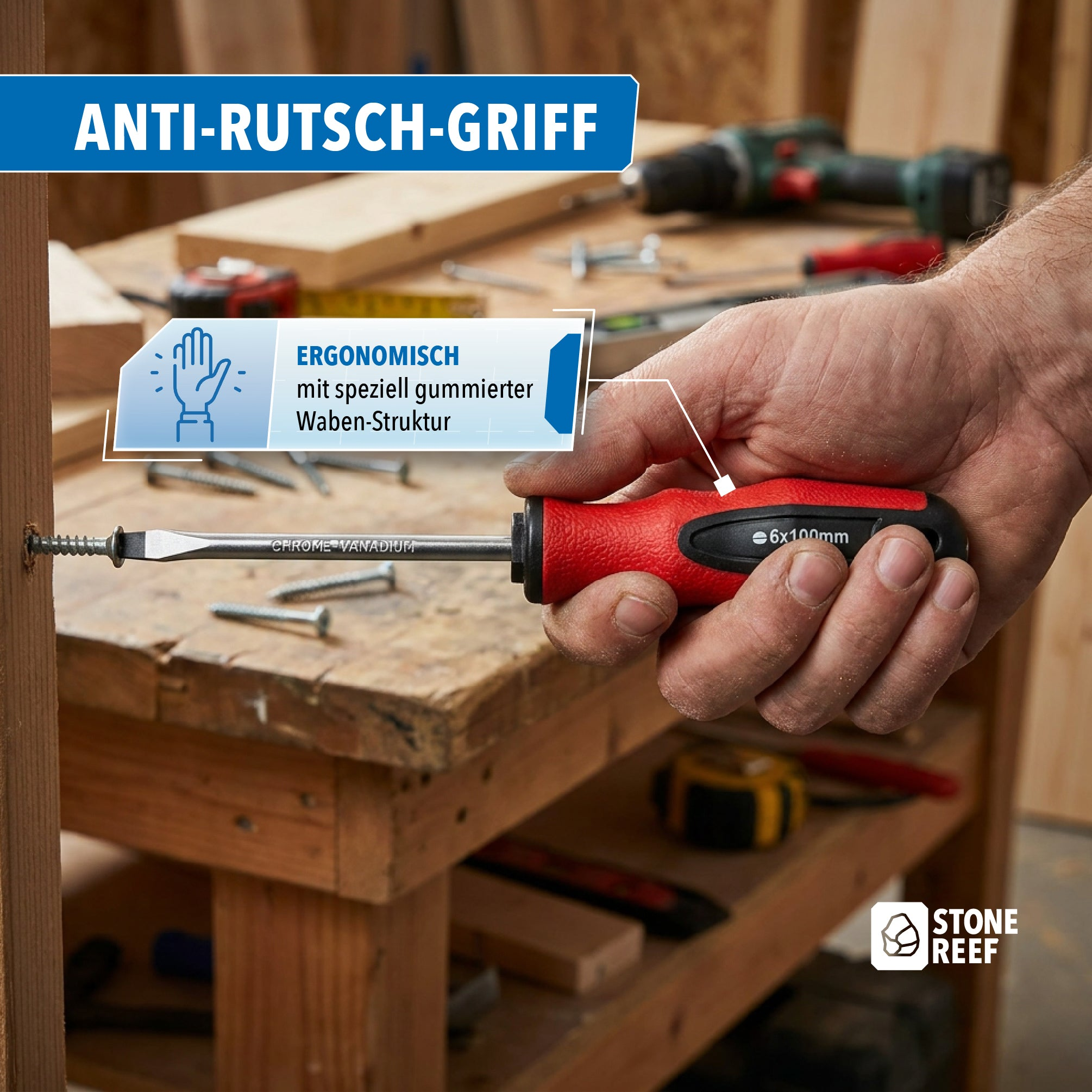 Hand hält einen ergonomischen Schraubenzieher mit rotem und schwarzem Griff über einer Werkbank.