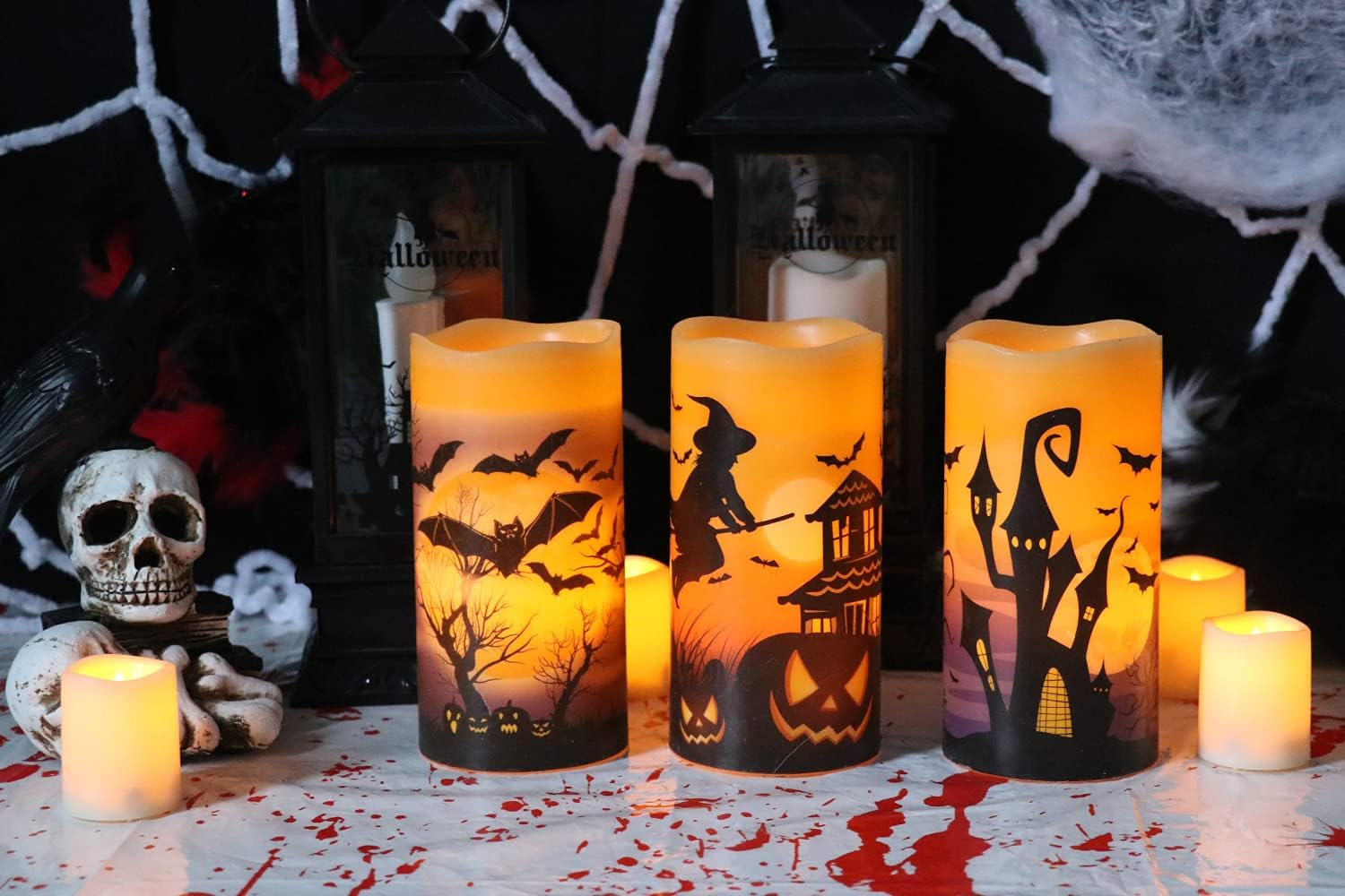 Drei leuchtende Halloween-Kerzen mit Silhouetten von Fledermäusen, einer Hexe und einem Spukhaus.