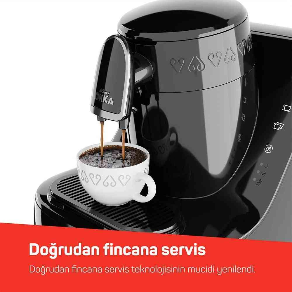 Una macchina da caffè nera versa il caffè in una tazza bianca su un vassoio raccogligocce.
