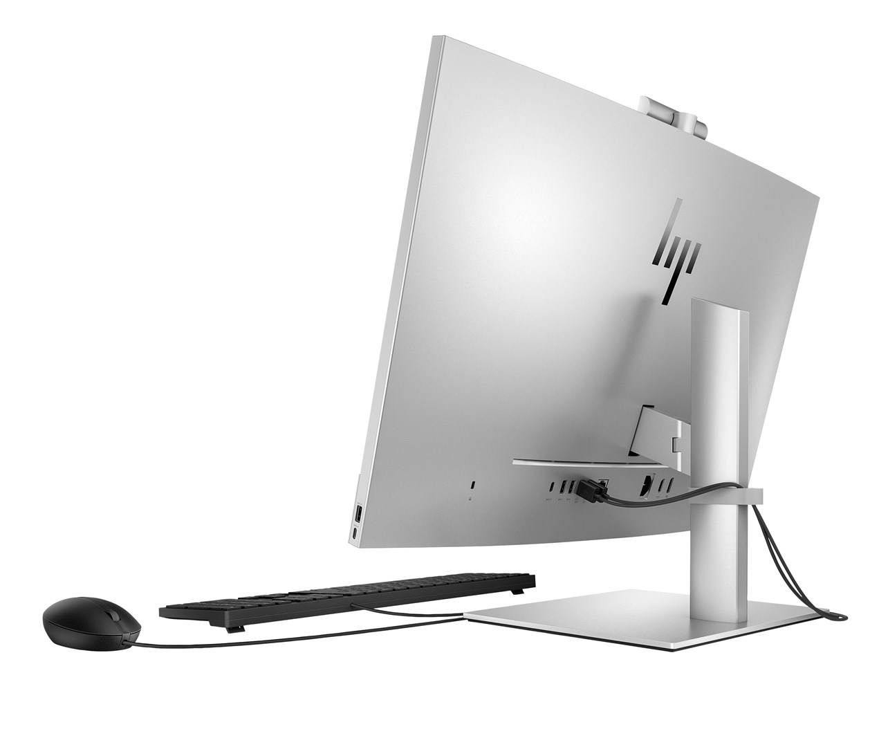 Widok z tyłu srebrnego komputera All-in-One HP z czarną myszką i klawiaturą na białym tle.