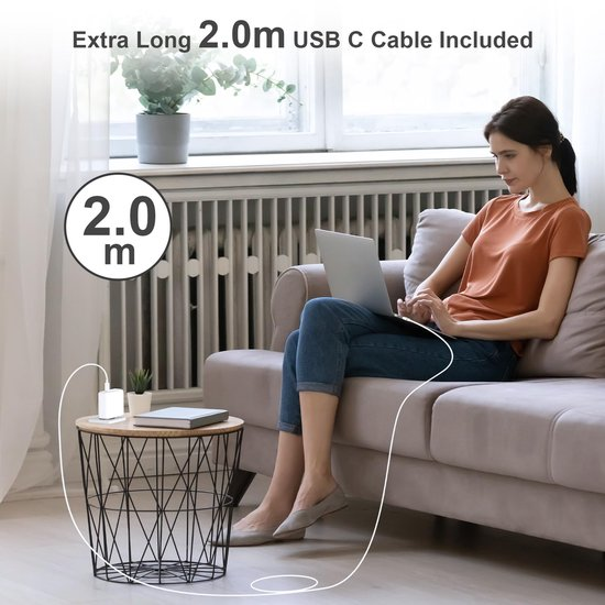 Frau sitzt auf dem Sofa und arbeitet am Laptop neben einem kleinen Drahttisch mit angeschlossenem USB-C-Kabel.