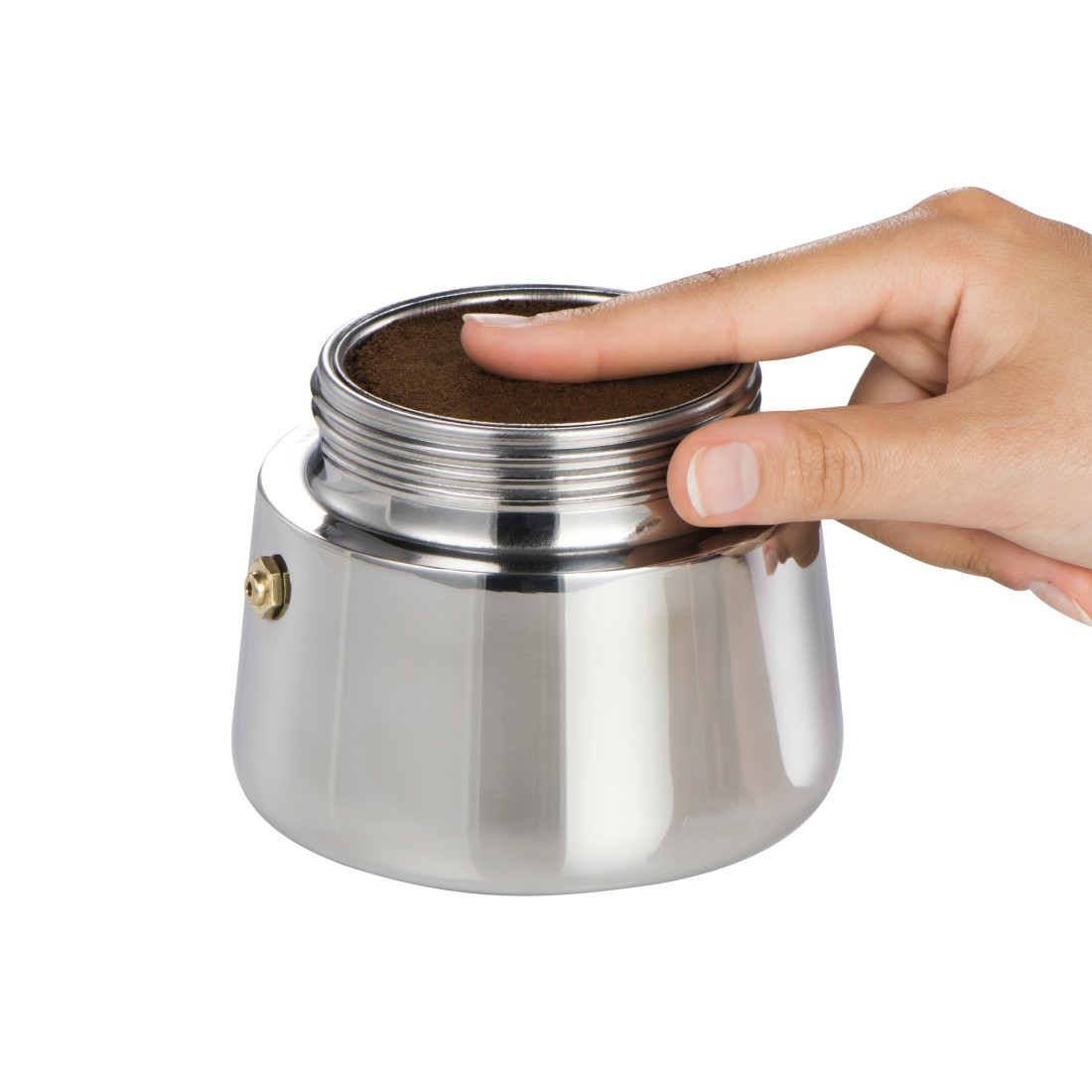 Una mano pressa leggermente il caffè macinato nel filtro di una moka argentata su sfondo bianco.