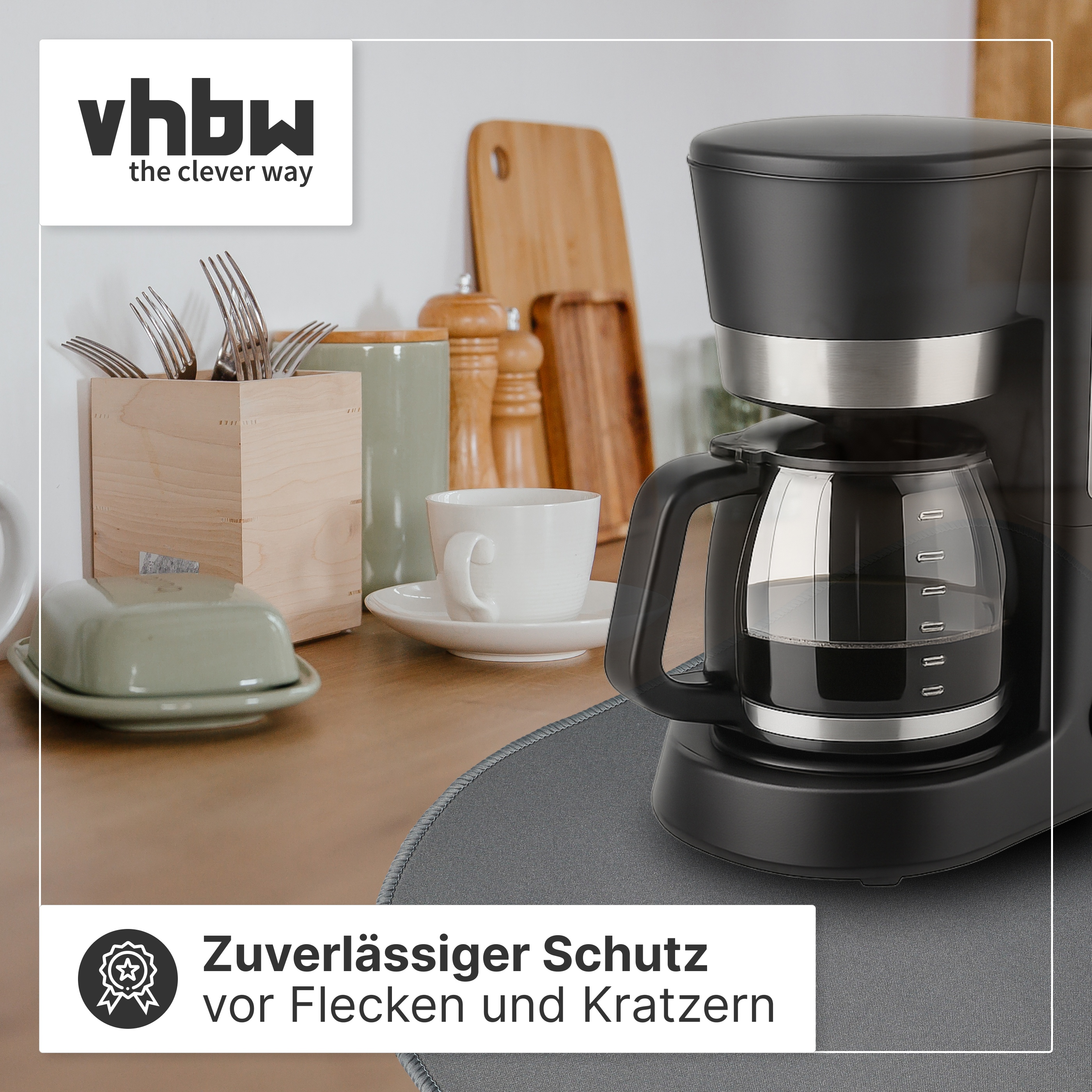 Eine schwarze Kaffeemaschine steht auf einer grauen Matte in einer Küche mit Holzoberflächen und Utensilien.