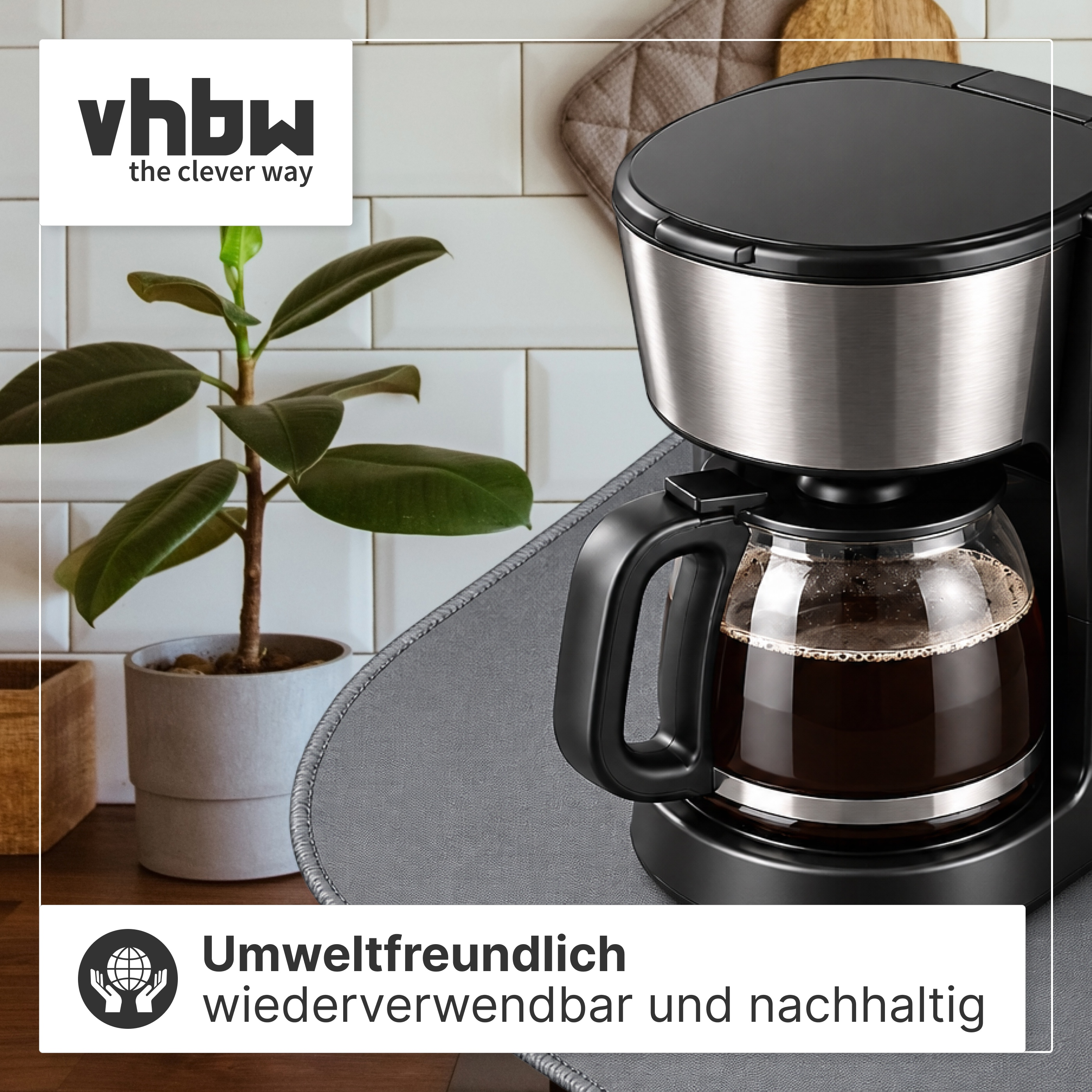 Eine schwarze Kaffeemaschine mit Glaskanne auf einem Tisch, im Hintergrund eine Topfpflanze.