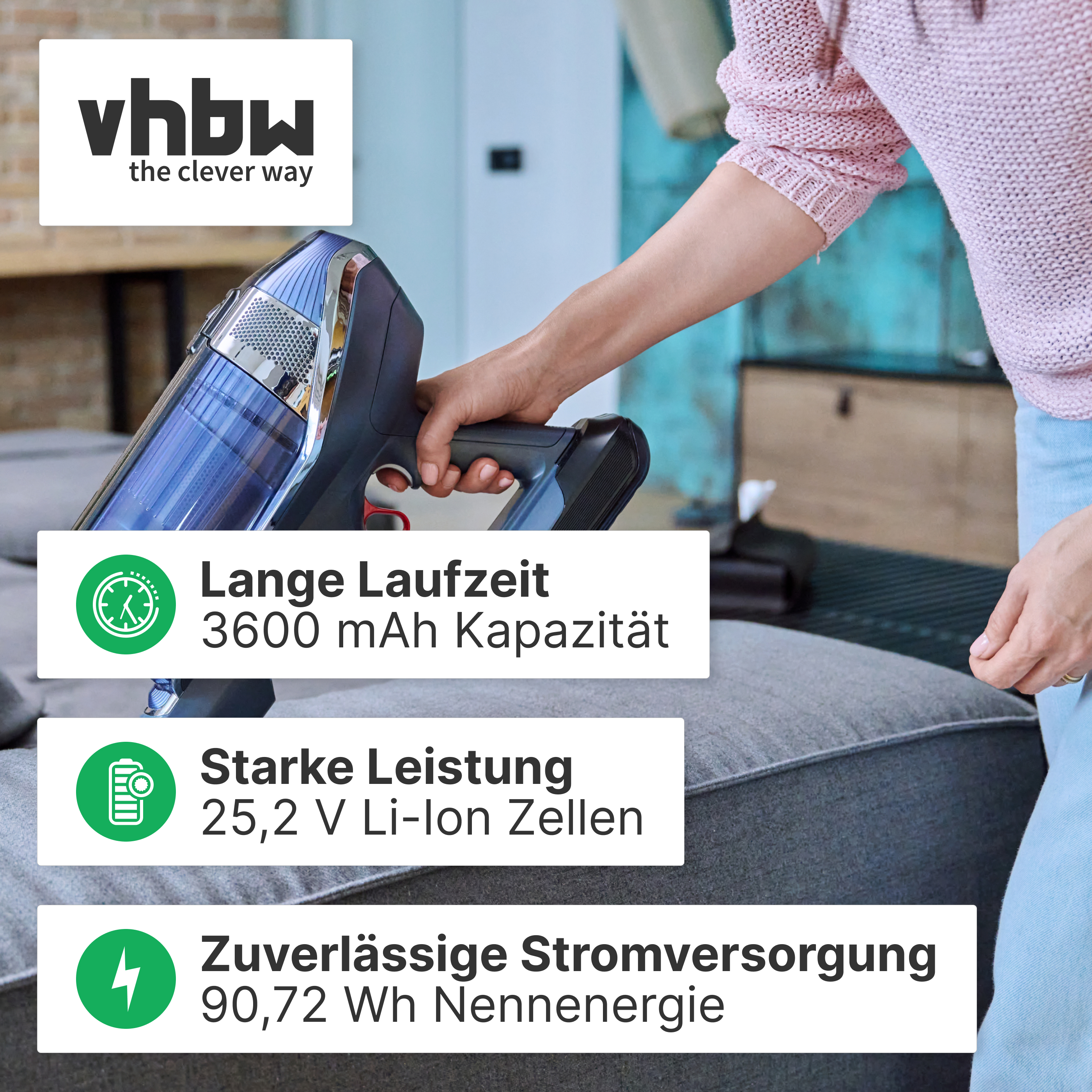 Eine Person saugt ein graues Sofa mit einem Akku-Handstaubsauger.