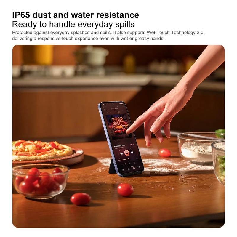 Una mano toca un teléfono inteligente en una cocina con pizza y tomates.