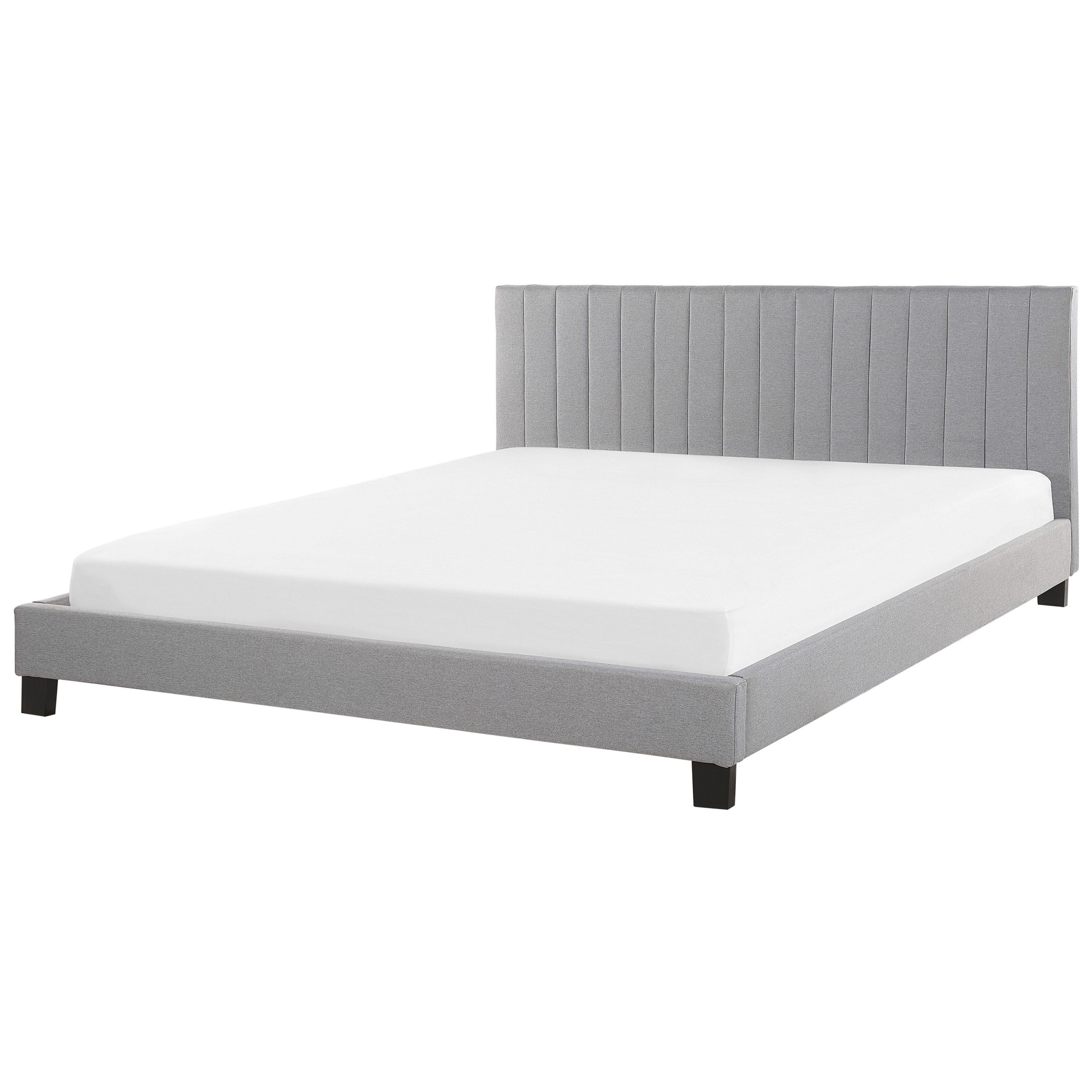 Un letto imbottito grigio con materasso bianco epiedi in legno scuro su sfondo bianco.