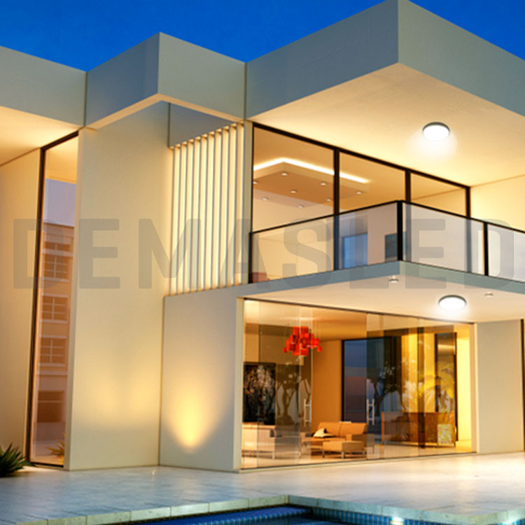 Una villa de lujo moderna al atardecer con luces de techo redondas iluminadas, grandes ventanas de vidrio y balcón.