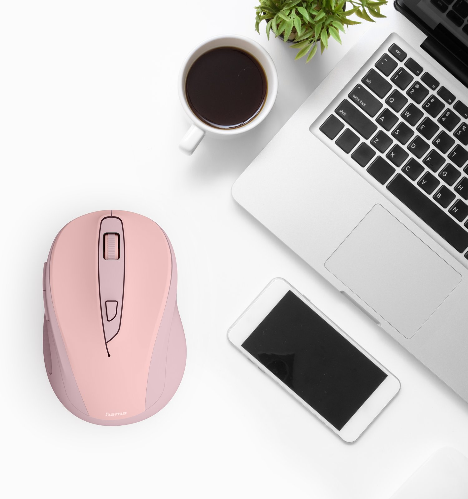 Ein weißer Schreibtisch mit rosa Computermaus, Laptop, Kaffeetasse, Smartphone und kleiner Pflanze.
