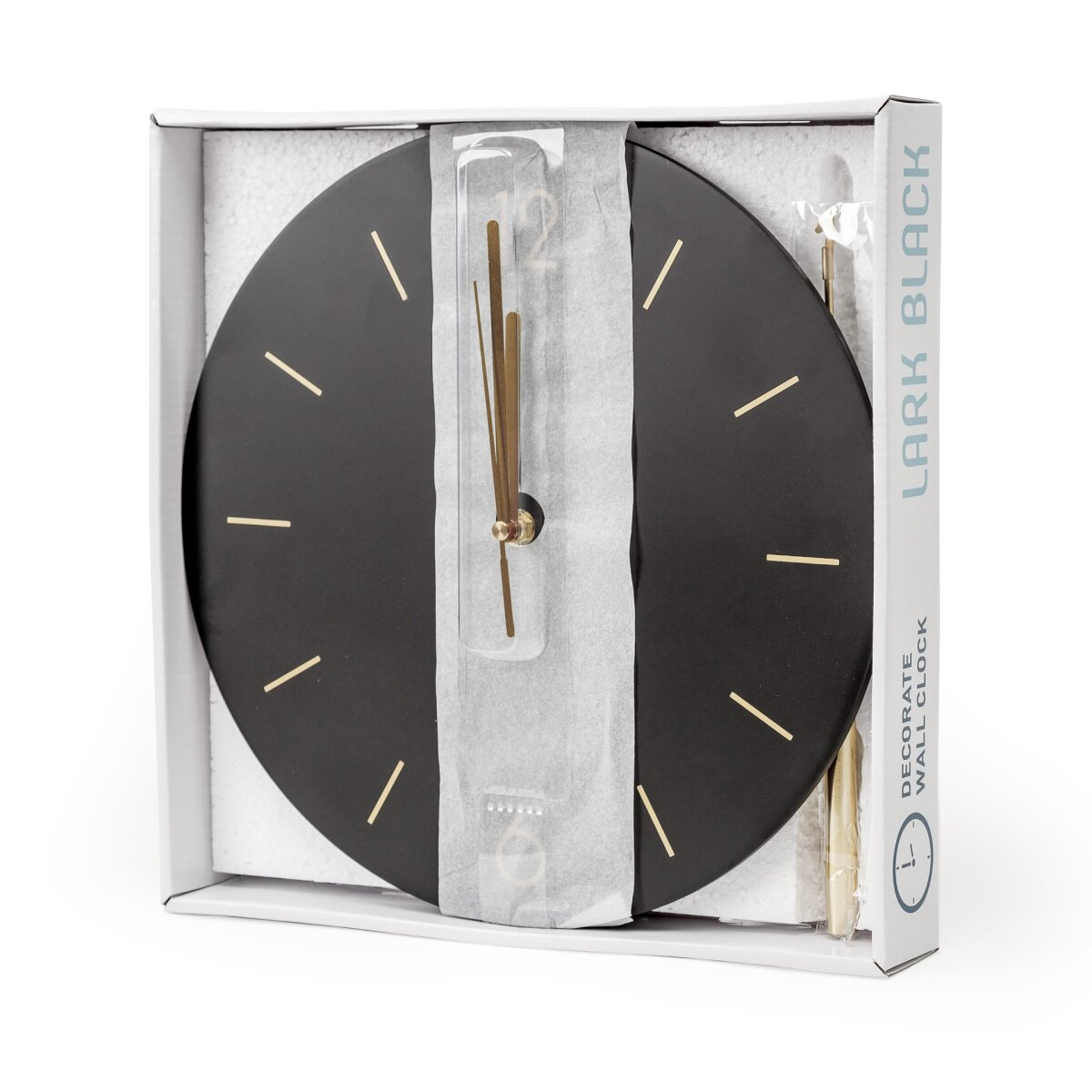 Eine schwarze Wanduhr mit goldenen Zeigern und Strichen, verpackt in einem weißen Karton.