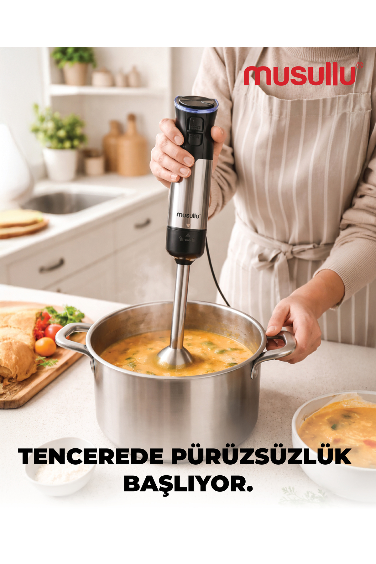 Bir kişi mutfaktaki tencere çorbayı el blenderiyle karıştırıyor.
