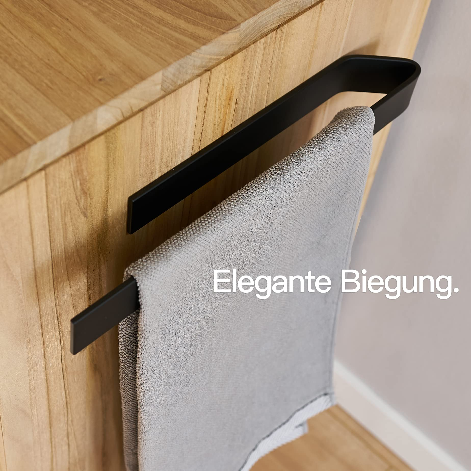 Ein schwarzer Handtuchhalter an einem Holzmöbel mit einem grauen Handtuch.