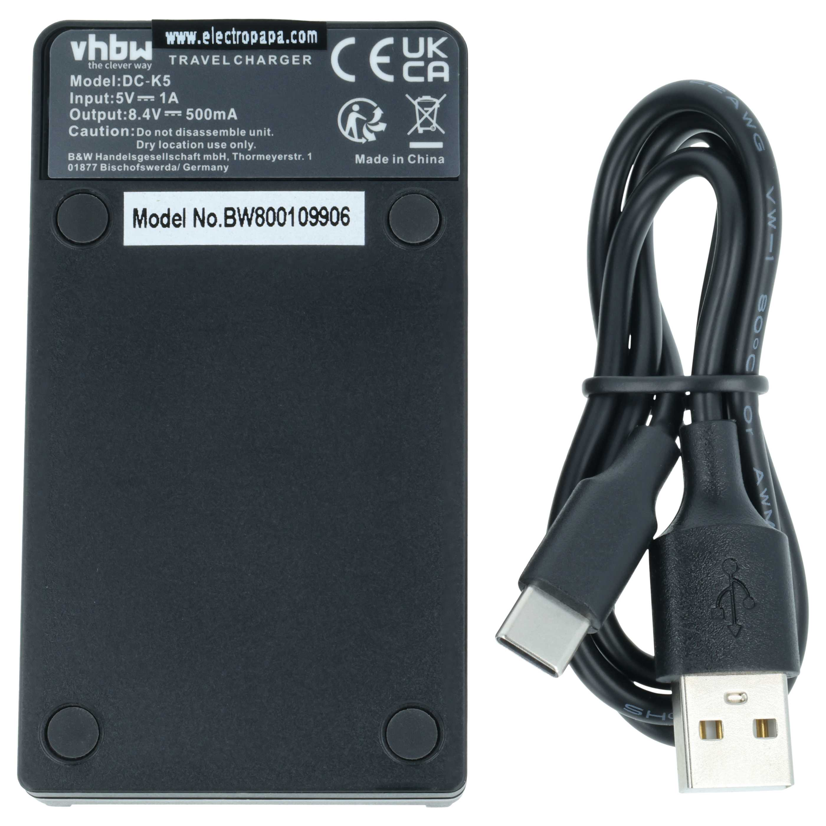Schwarzes Reiseladegerät mit technischen Daten auf dem Etikett und einem gebündelten USB-Kabel daneben.