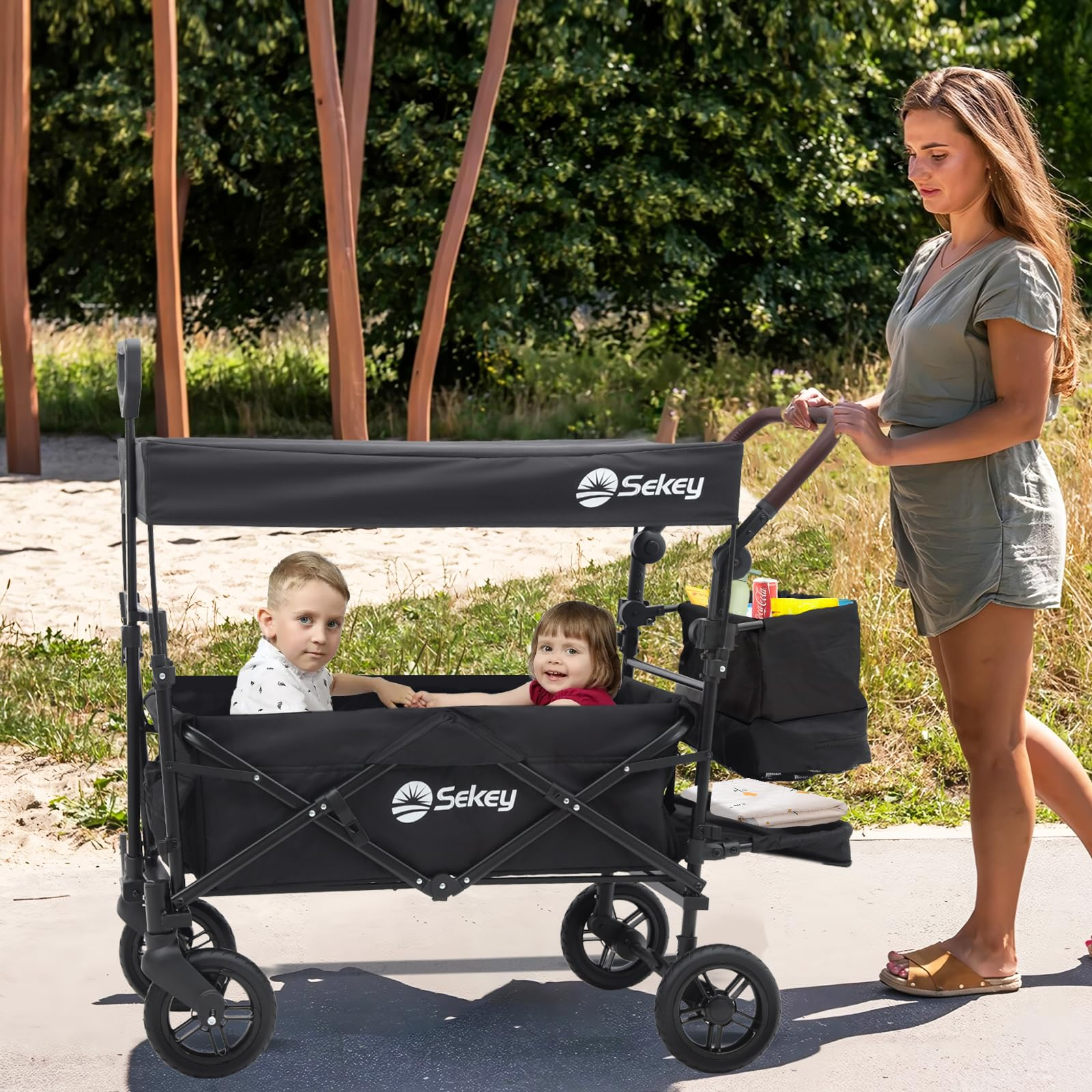 Une femme pousse un chariot noir Sekey avec deux enfants dans un parc.