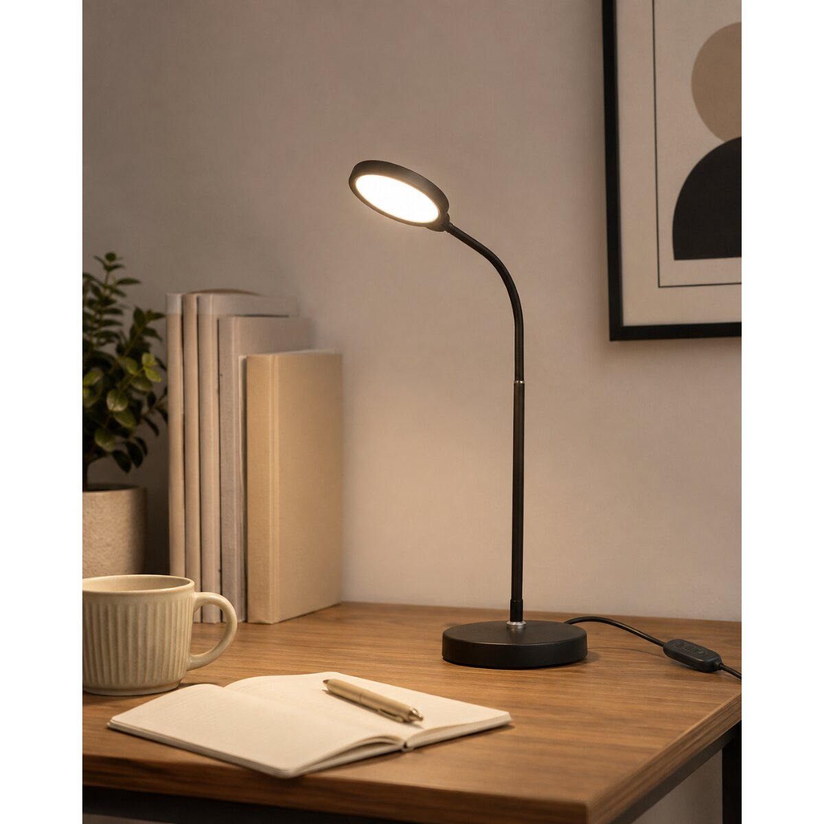 Eine schwarze Schreibtischlampe mit beleuchtetem Kopf steht auf einem Holztisch neben Büchern und einer Tasse.
